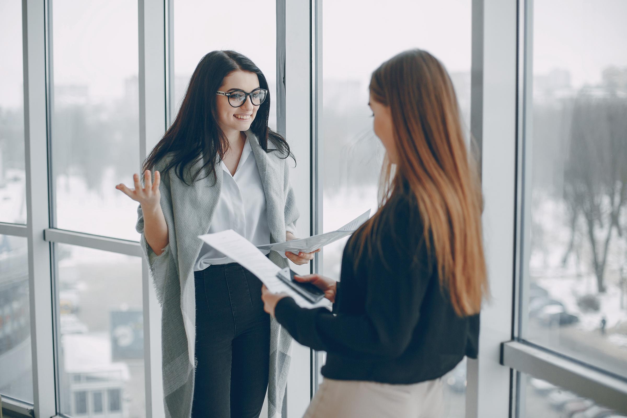 Una mujer sonriente hablando con su compañero de trabajo | Fuente: Freepik