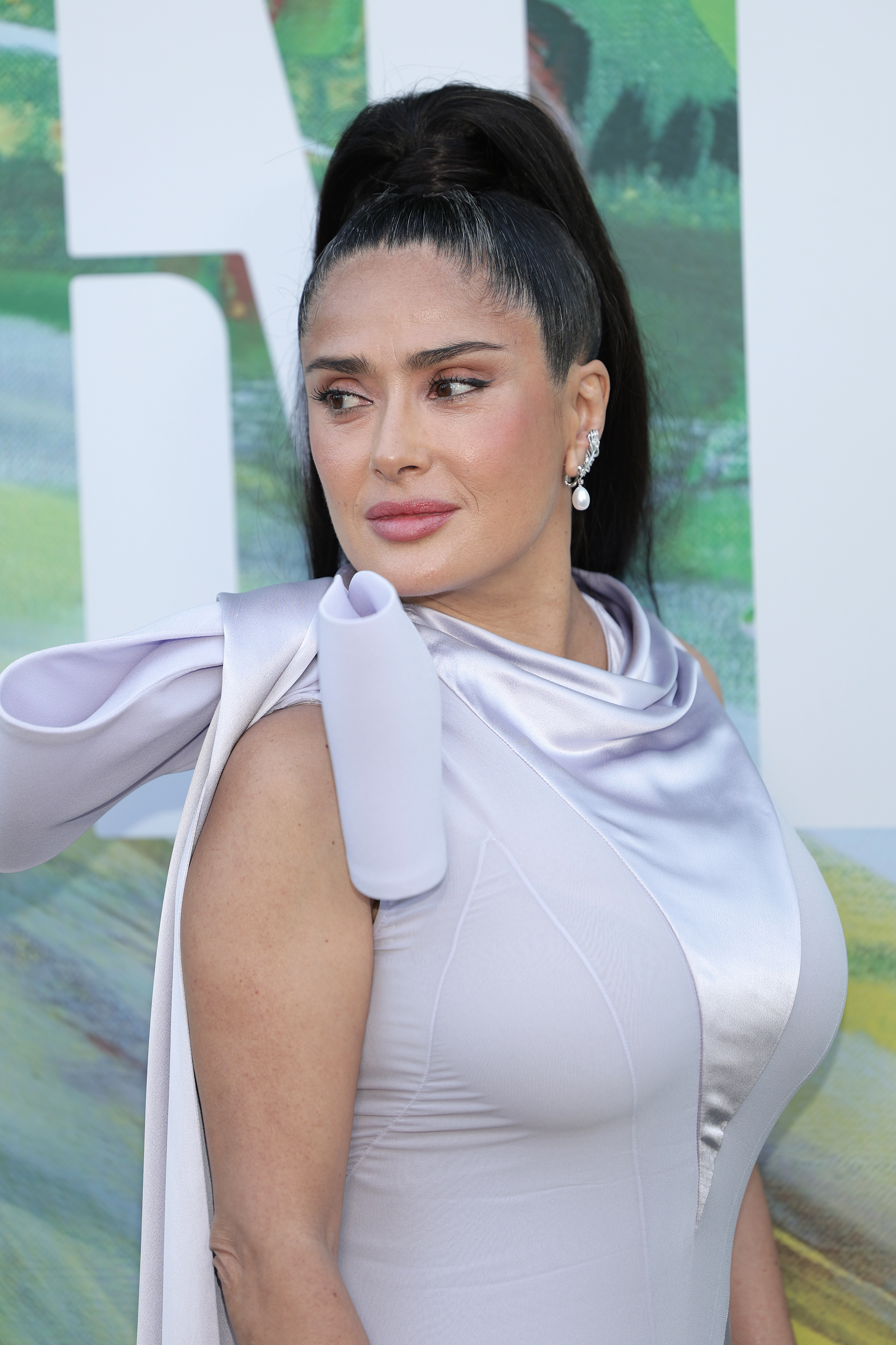 Salma Hayek a veces cambia sus características ondas castañas sueltas por elegantes recogidos, dejando ver en ocasiones las canas que tiene alrededor de la línea del pelo y que no siempre decide taparse. | Fuente: Getty Images