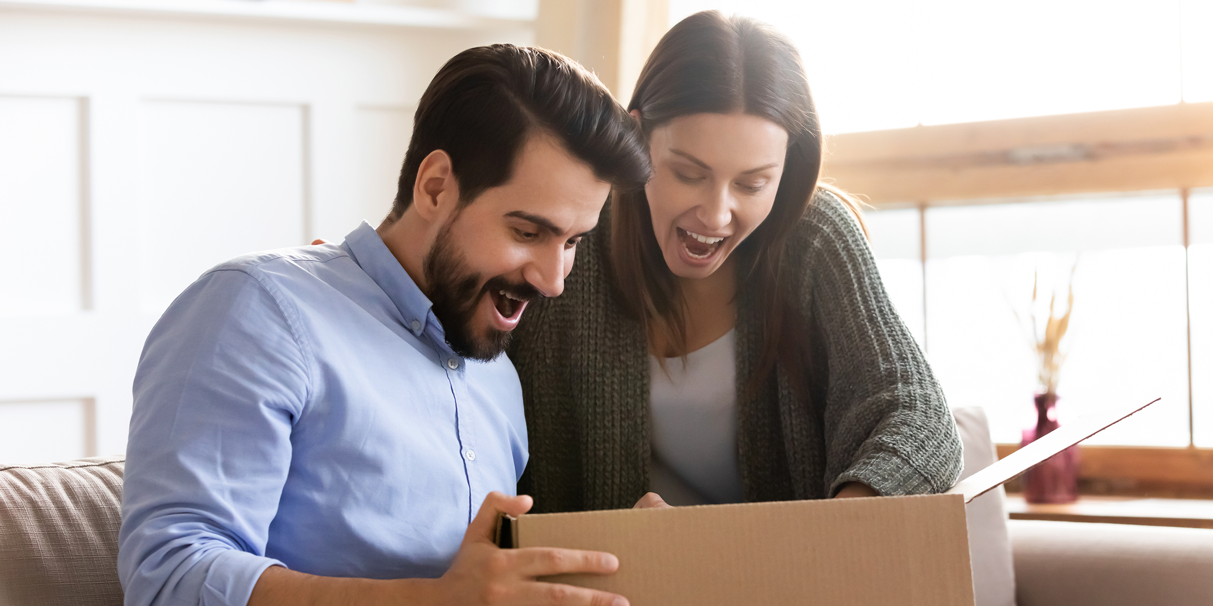 Una pareja sorprendida mirando una caja abierta | Fuente: Shutterstock