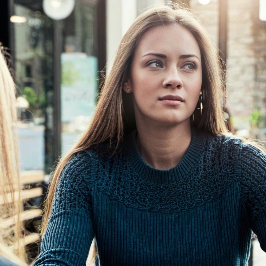 Una mujer sentada al aire libre y mirando hacia | Fuente: Midjourney