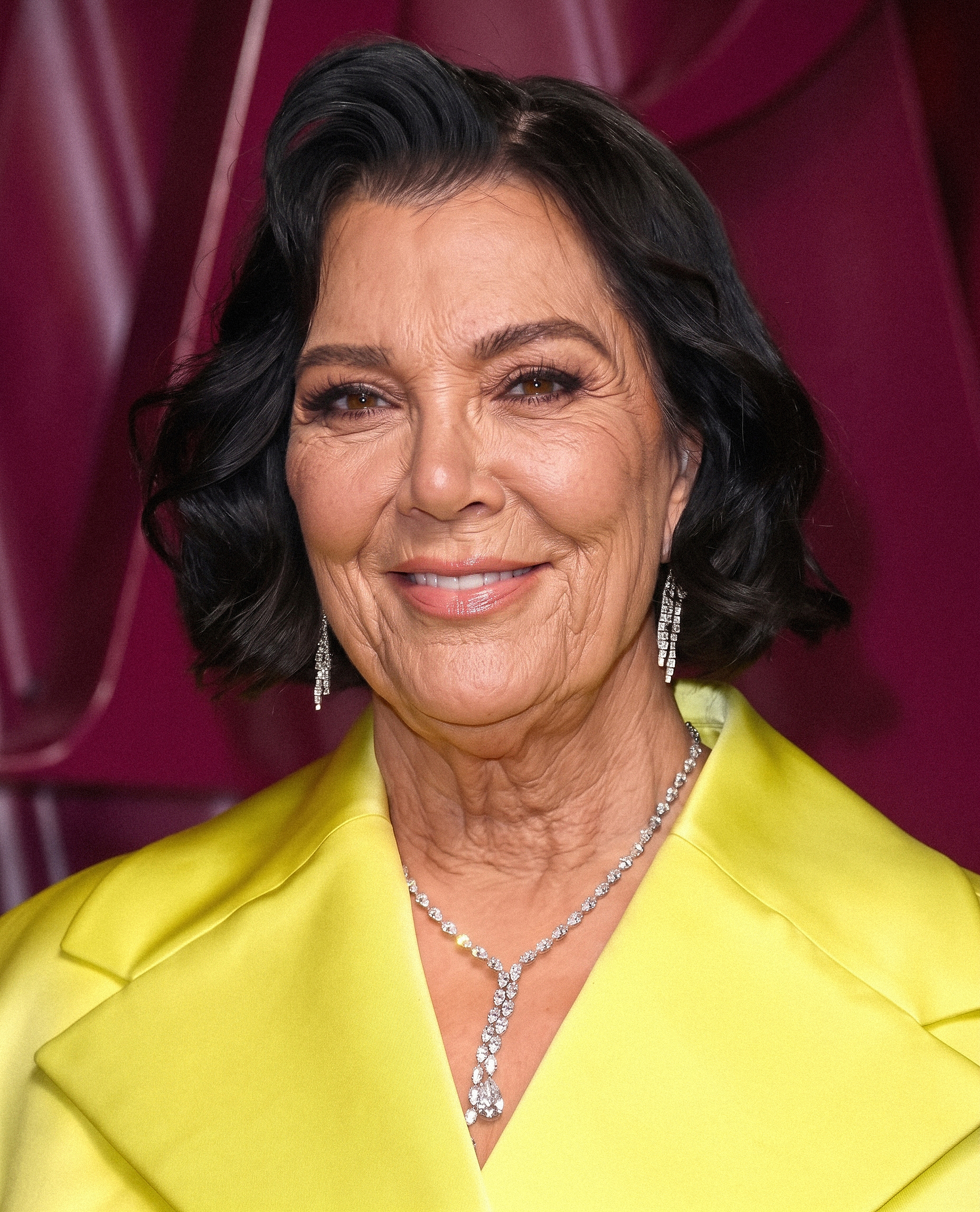 Con una chaqueta amarilla brillante, Kris luce un corte bob de estilo suave, mientras las arruguitas naturales que se le marcan alrededor de los ojos, las mejillas y el cuello se convierten en parte del retrato imaginario. | Fuente: Gemini