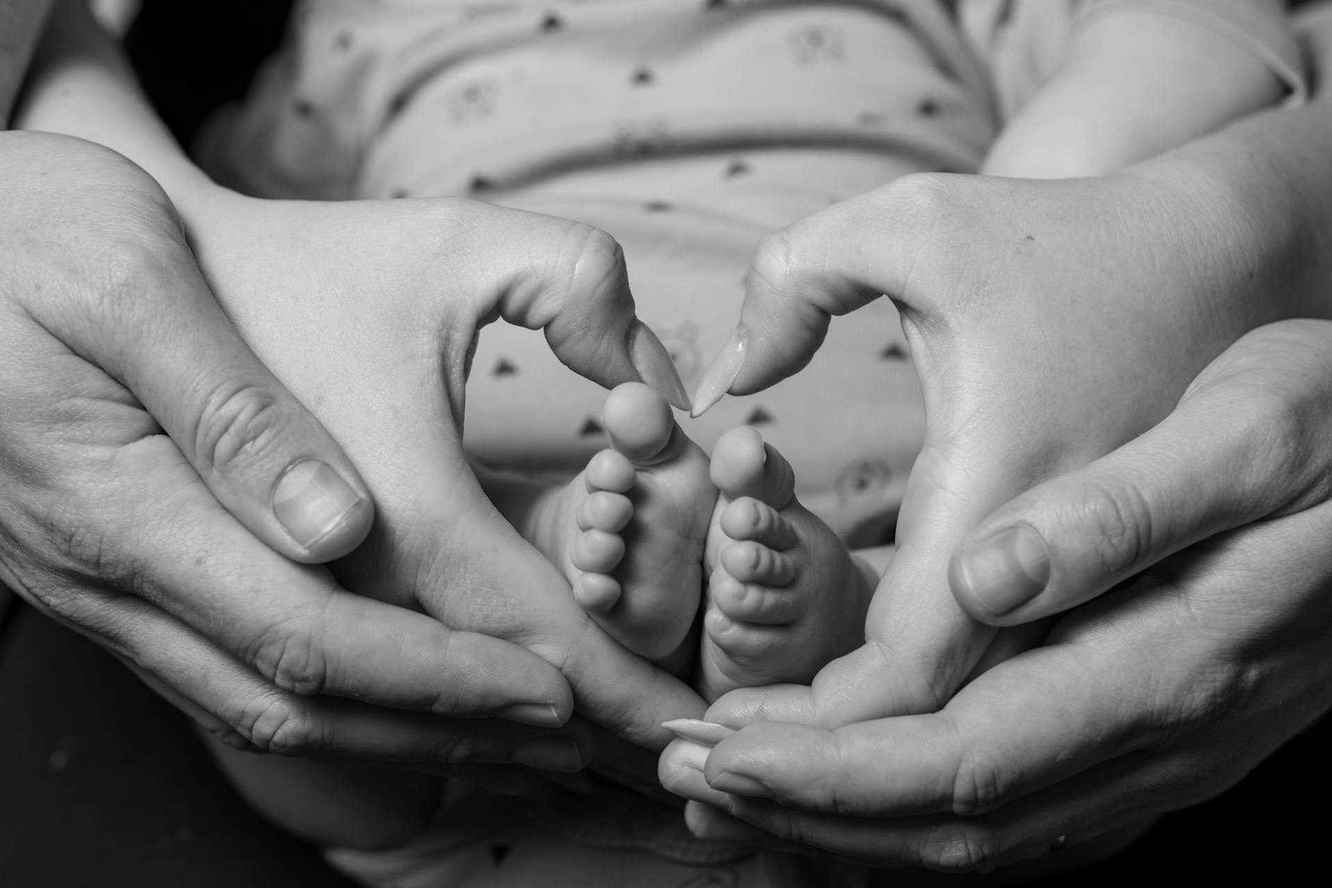 Una coppia che fa un segno a forma di cuore intorno ai piedini del proprio bambino | Fonte: Pexels