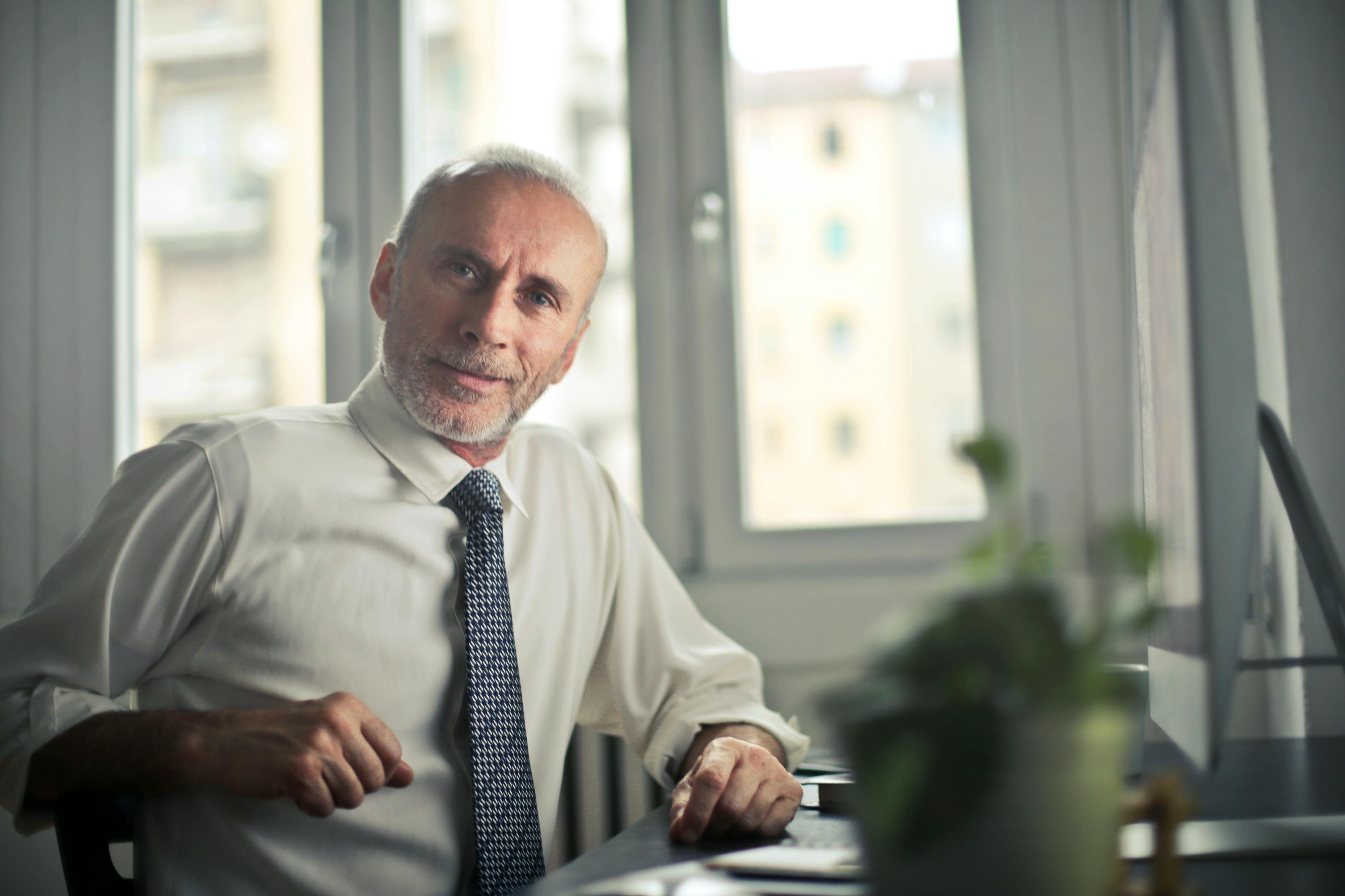 Un hombre de mediana edad vestido de etiqueta sentado en una mesa | Fuente: Pexels