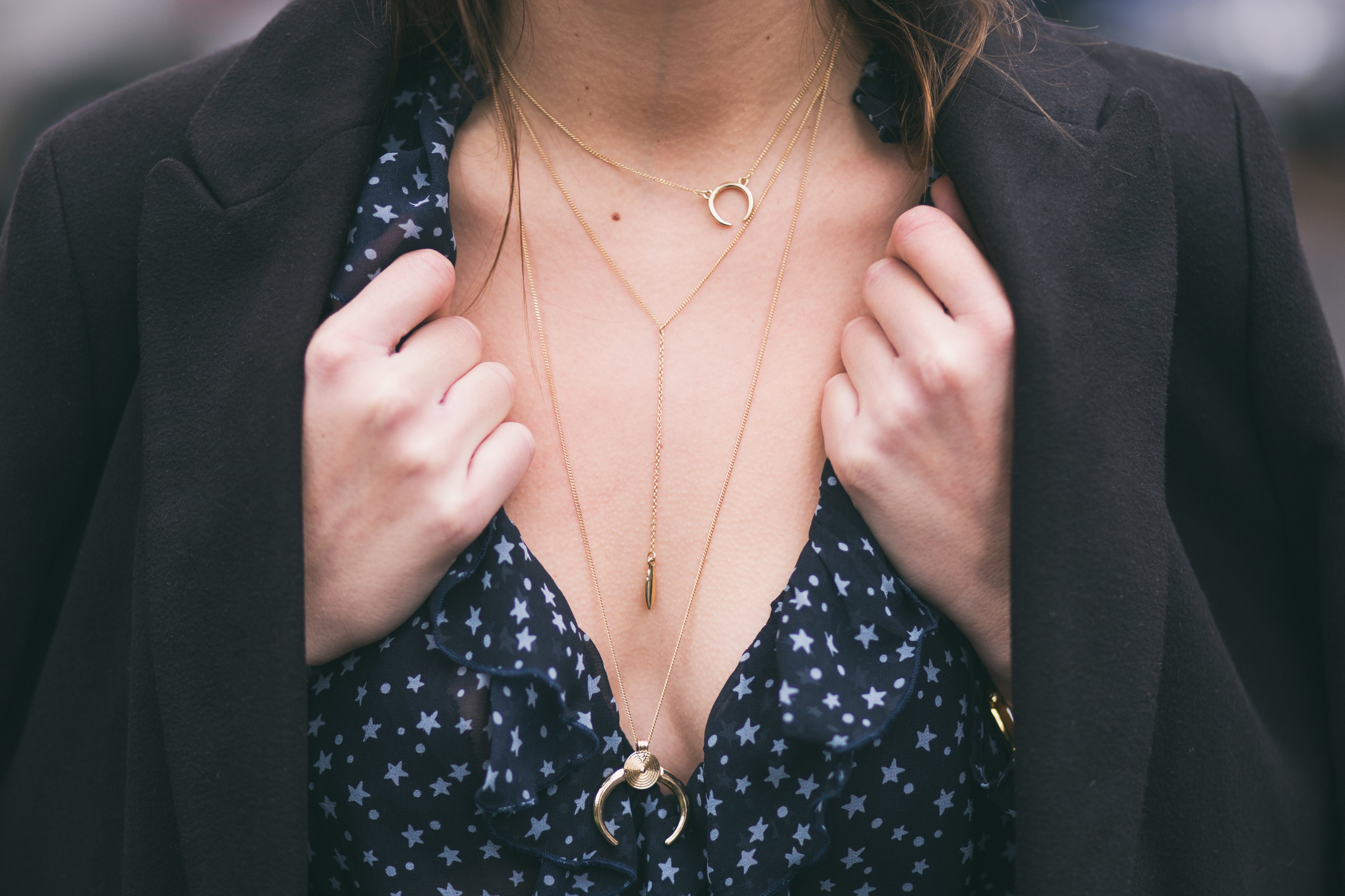 Blogger de moda cob un elegante abrigo negro, una camisa con escote en V y un hermoso moderno collar con cadena de oro. Fuente: Shuttterstock