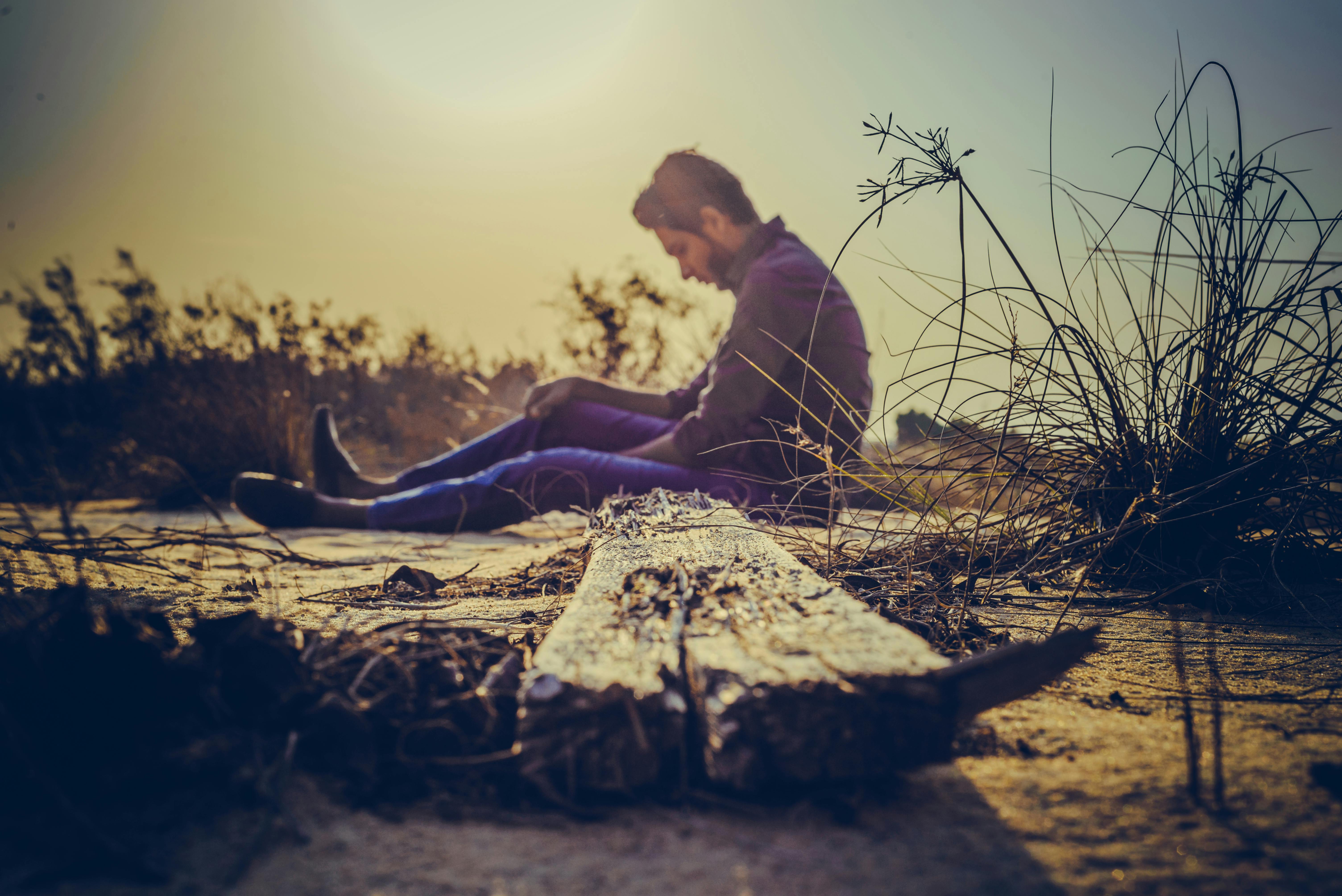 Hombre triste sentado a un lado de la carretera | Fuente: Pexels