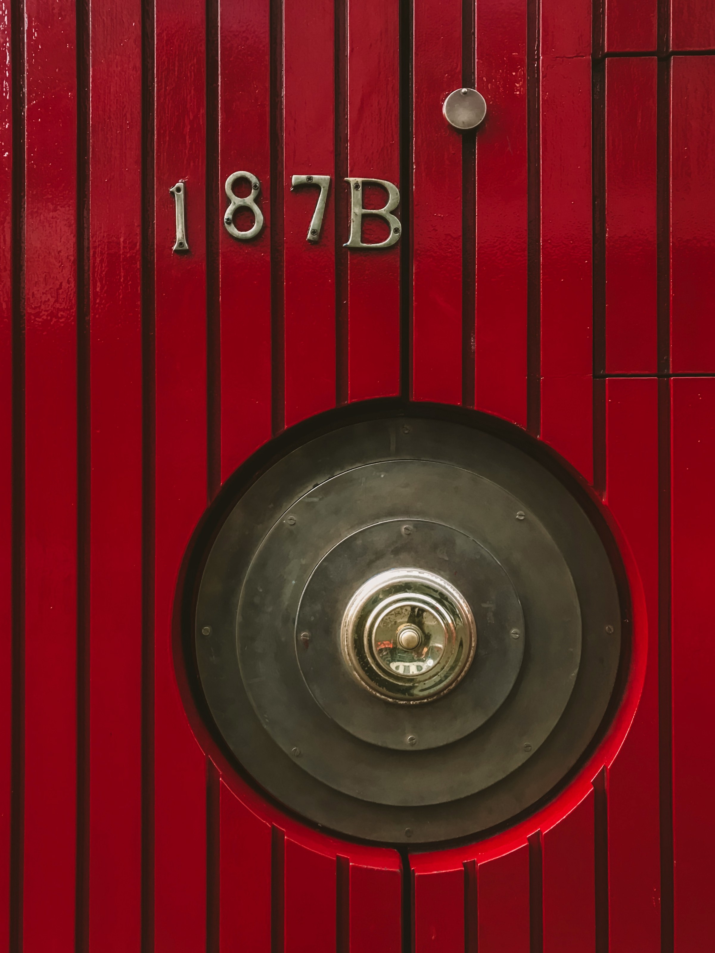Una puerta roja con un pomo metálico | Fuente: Unsplash