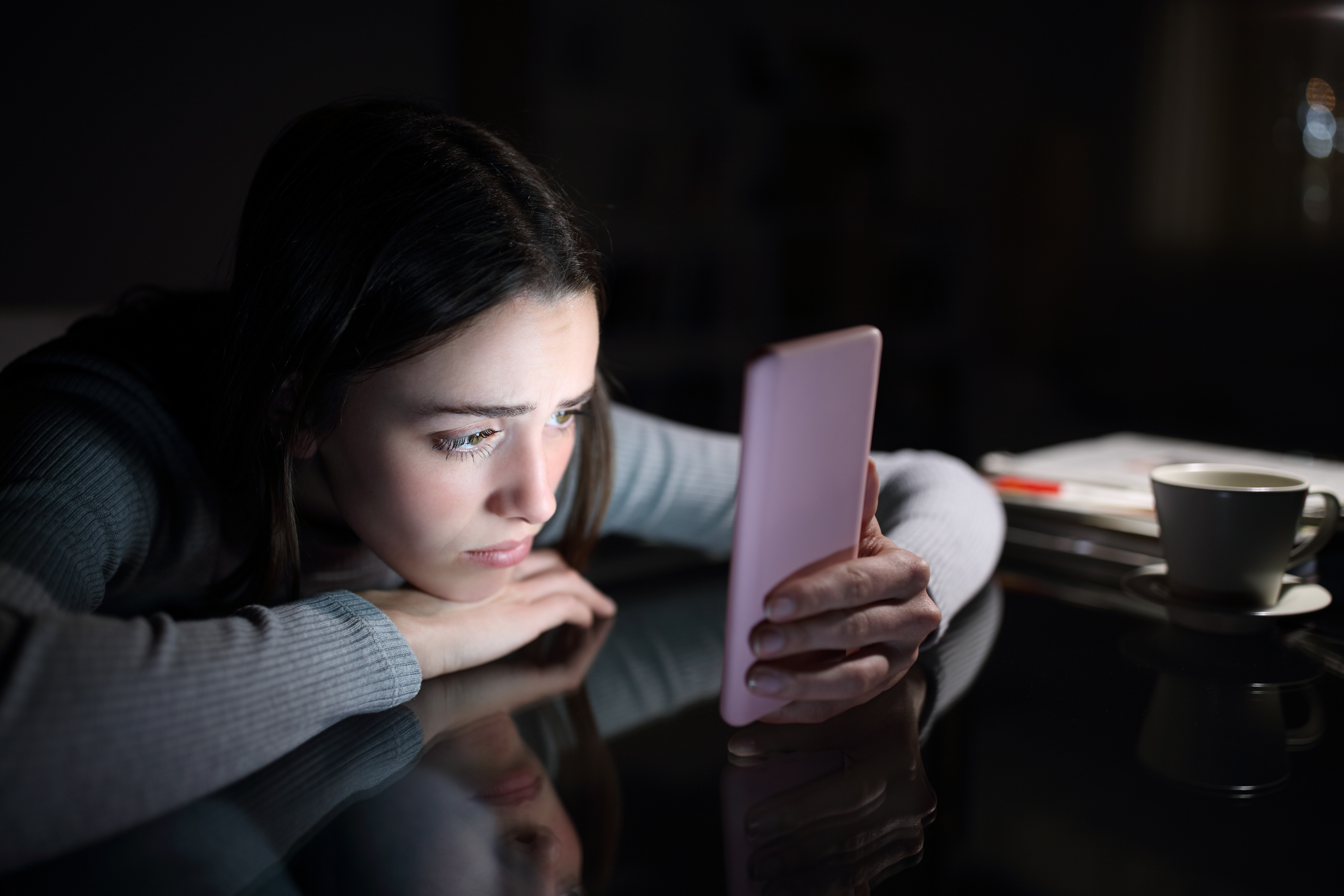 Mujer triste consultando su smartphone | Fuente: Shutterstock