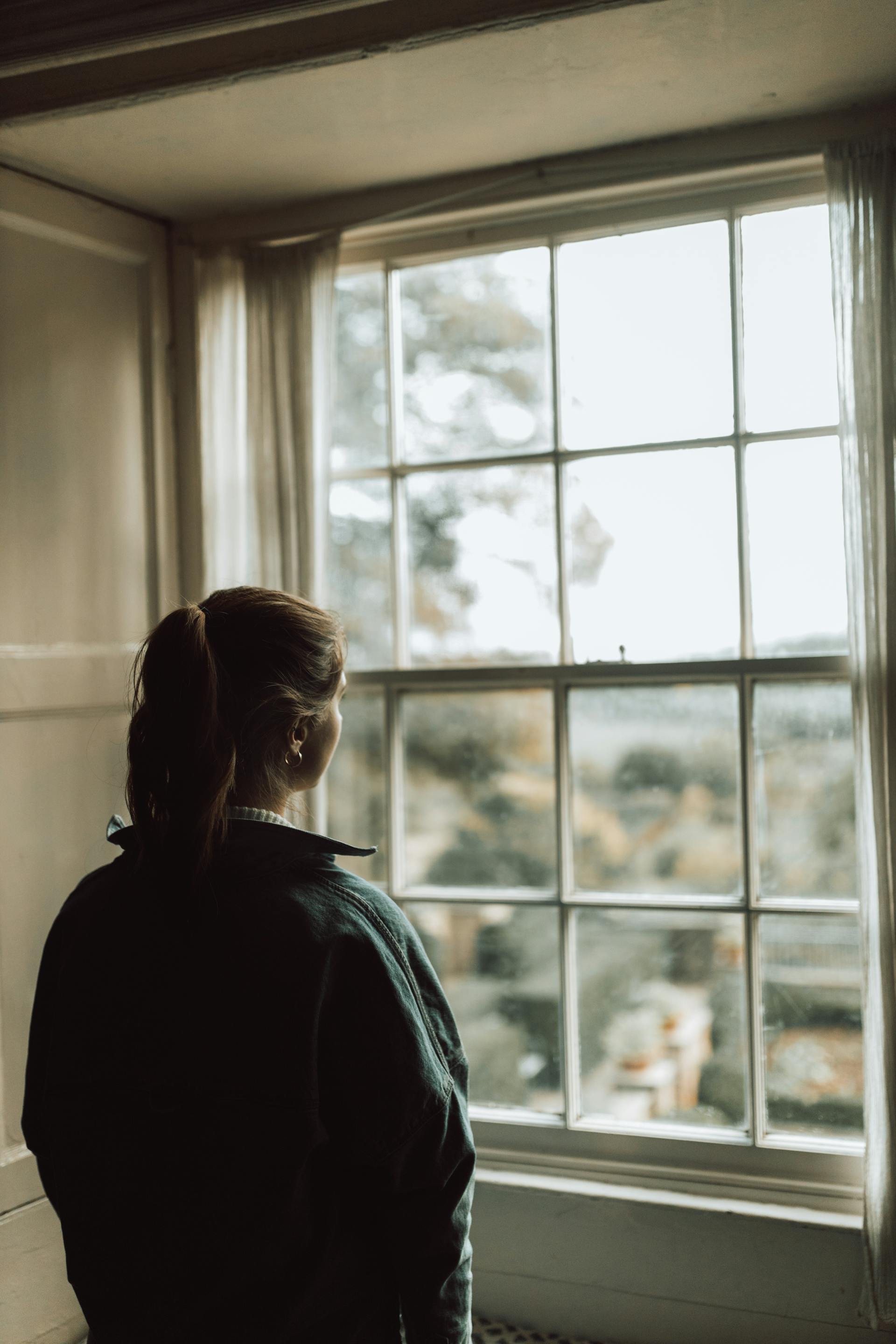 Una mujer mirando por la ventana | Fuente: Pexels