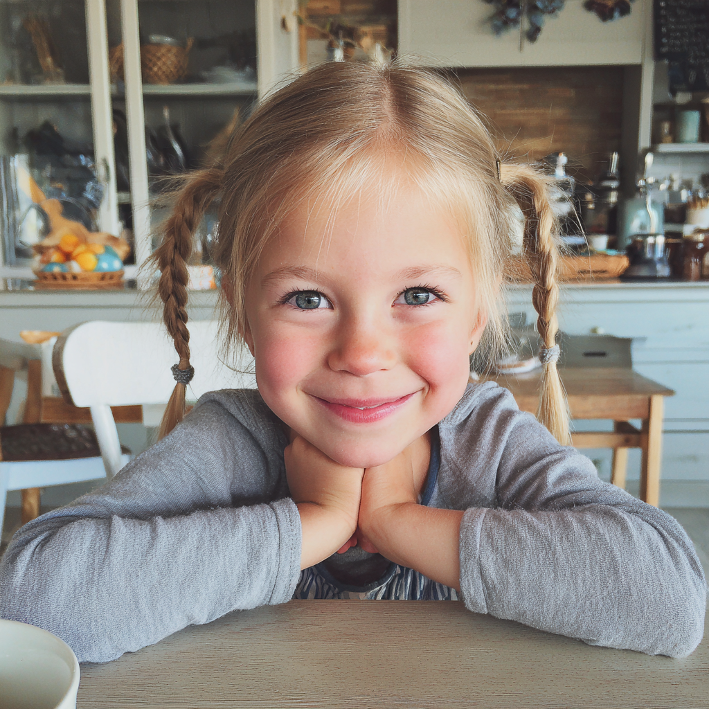 Una bambina sorridente seduta al tavolo della colazione | Fonte: Midjourney