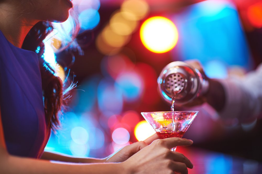 Chica joven sostiene una copa de martini en un bar. | Imagen: Shutterstock