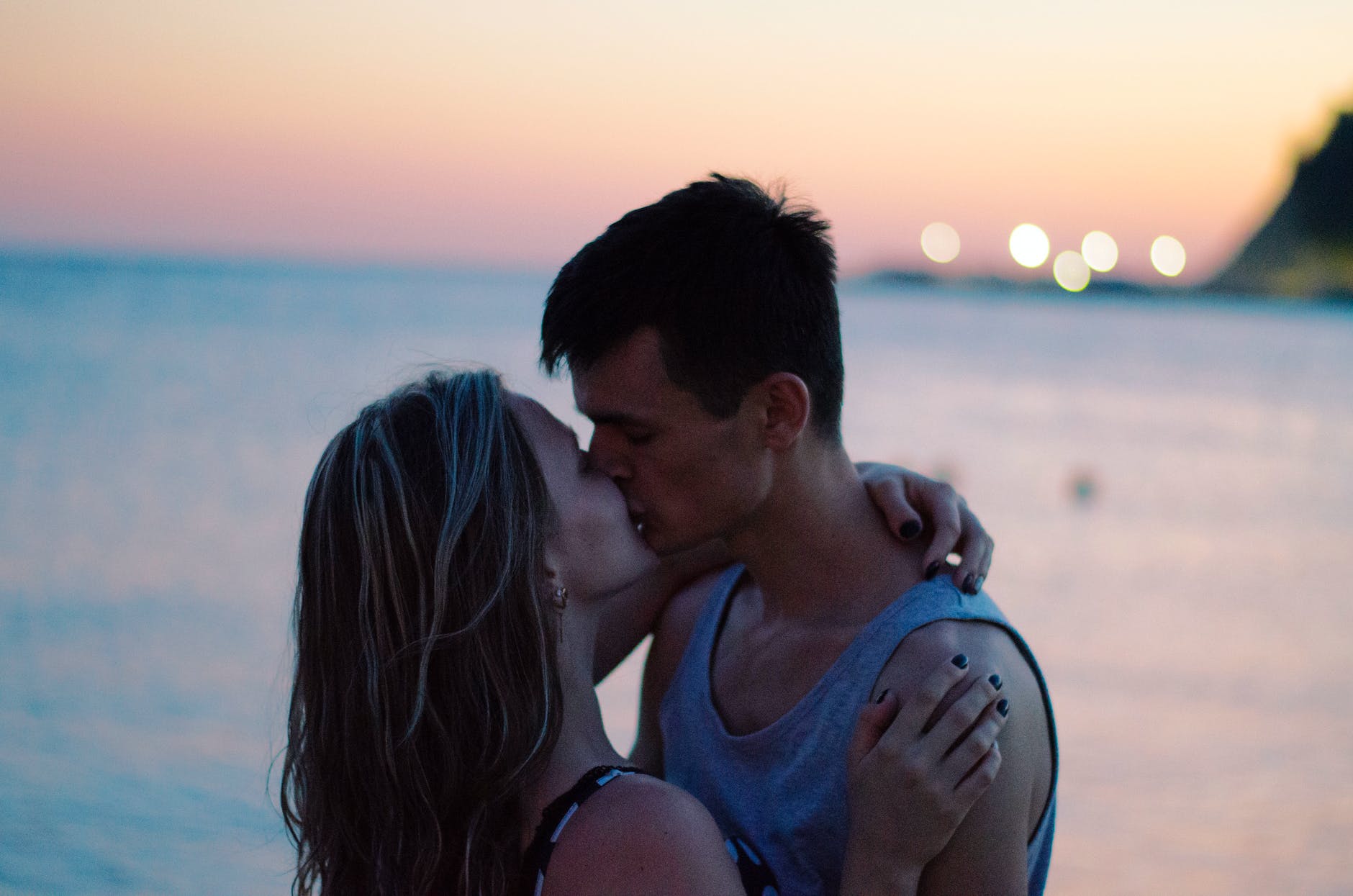 Pareja enamorada besándose con el mar en el fondo. | Foto: Pexels