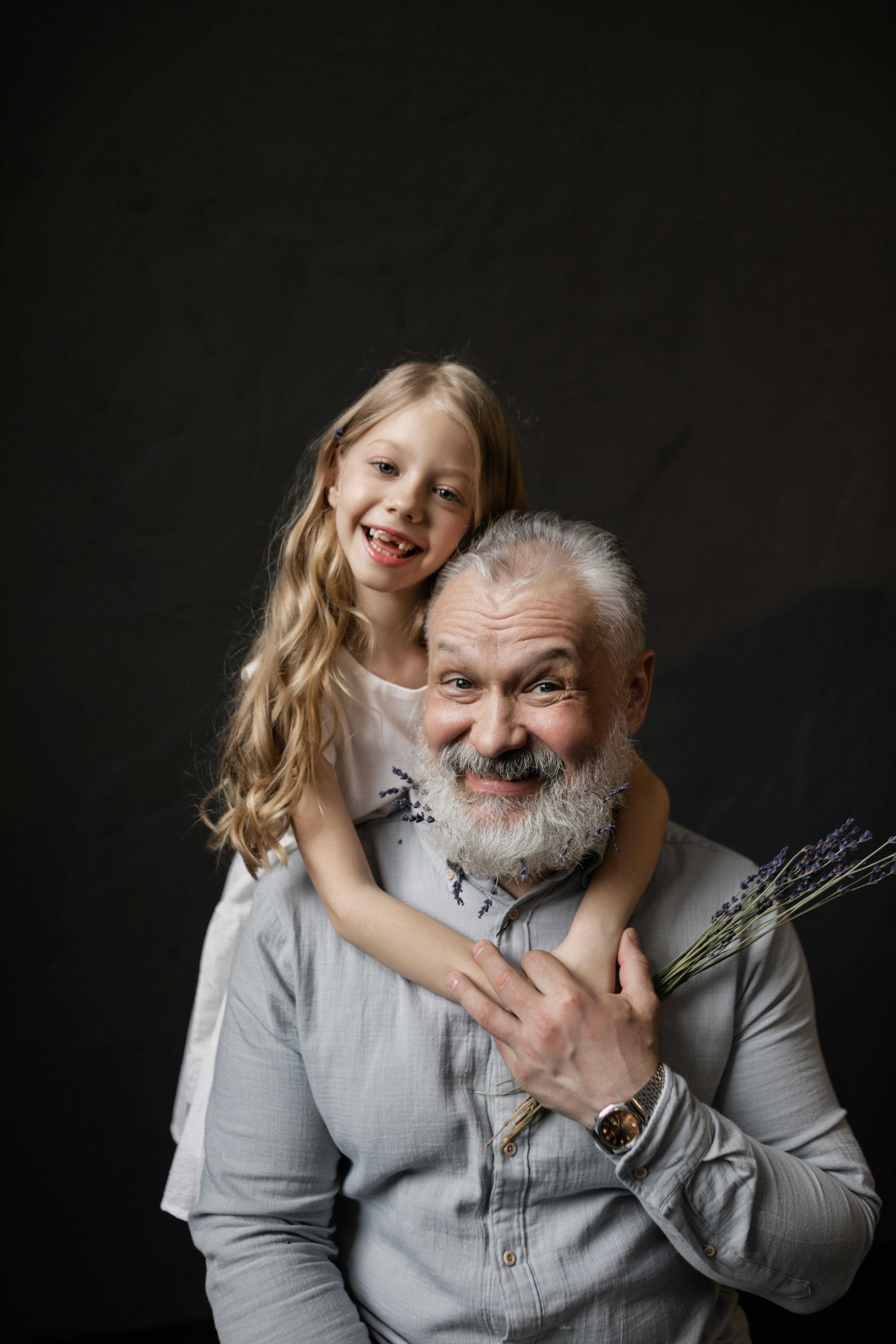 Una niña abrazando a su abuelo por detrás | Fuente: Pexels