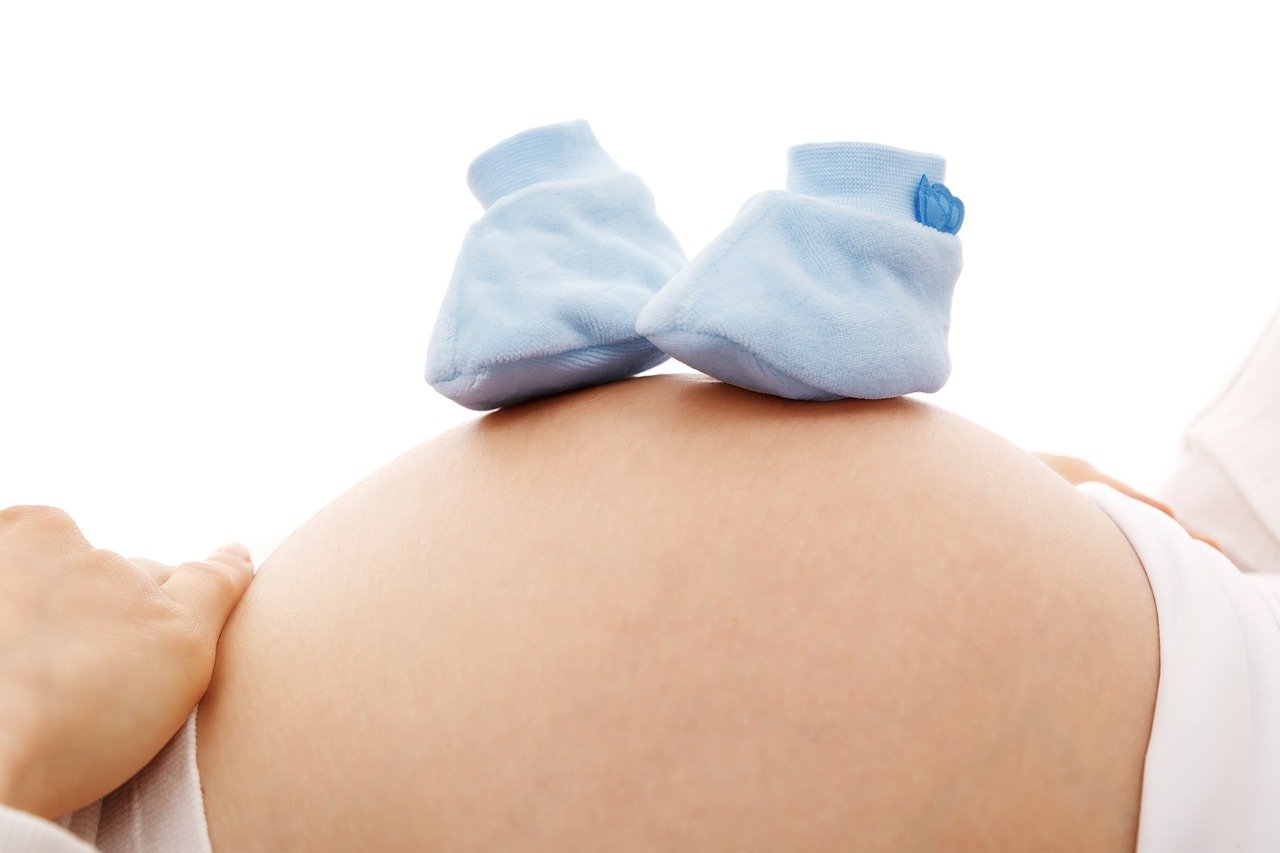 Vientre de embarazada con botitas de bebé azules. | Foto: Pixabay