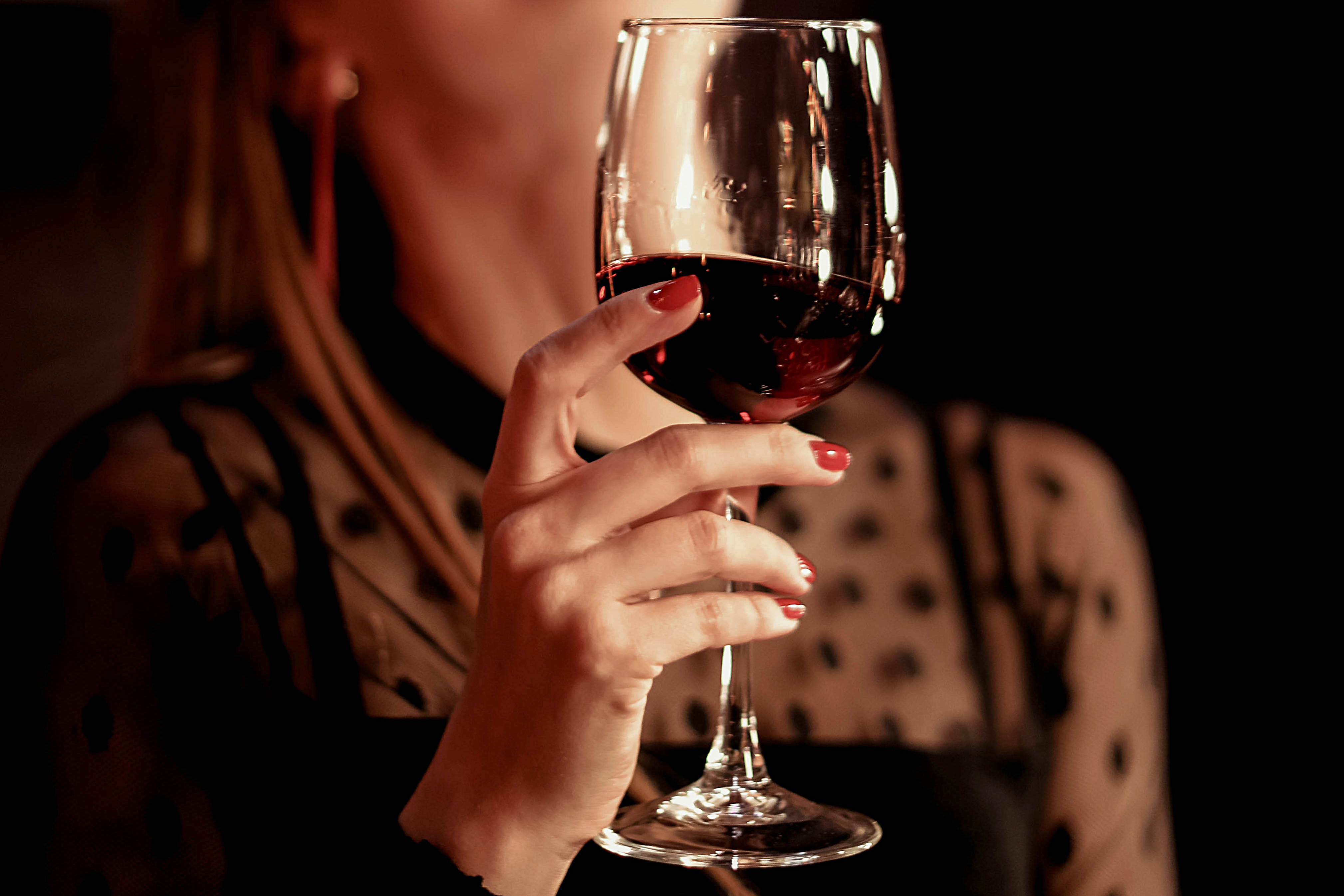 Mano femenina sosteniendo un vaso de vino tinto | Fuente: Shutterstock