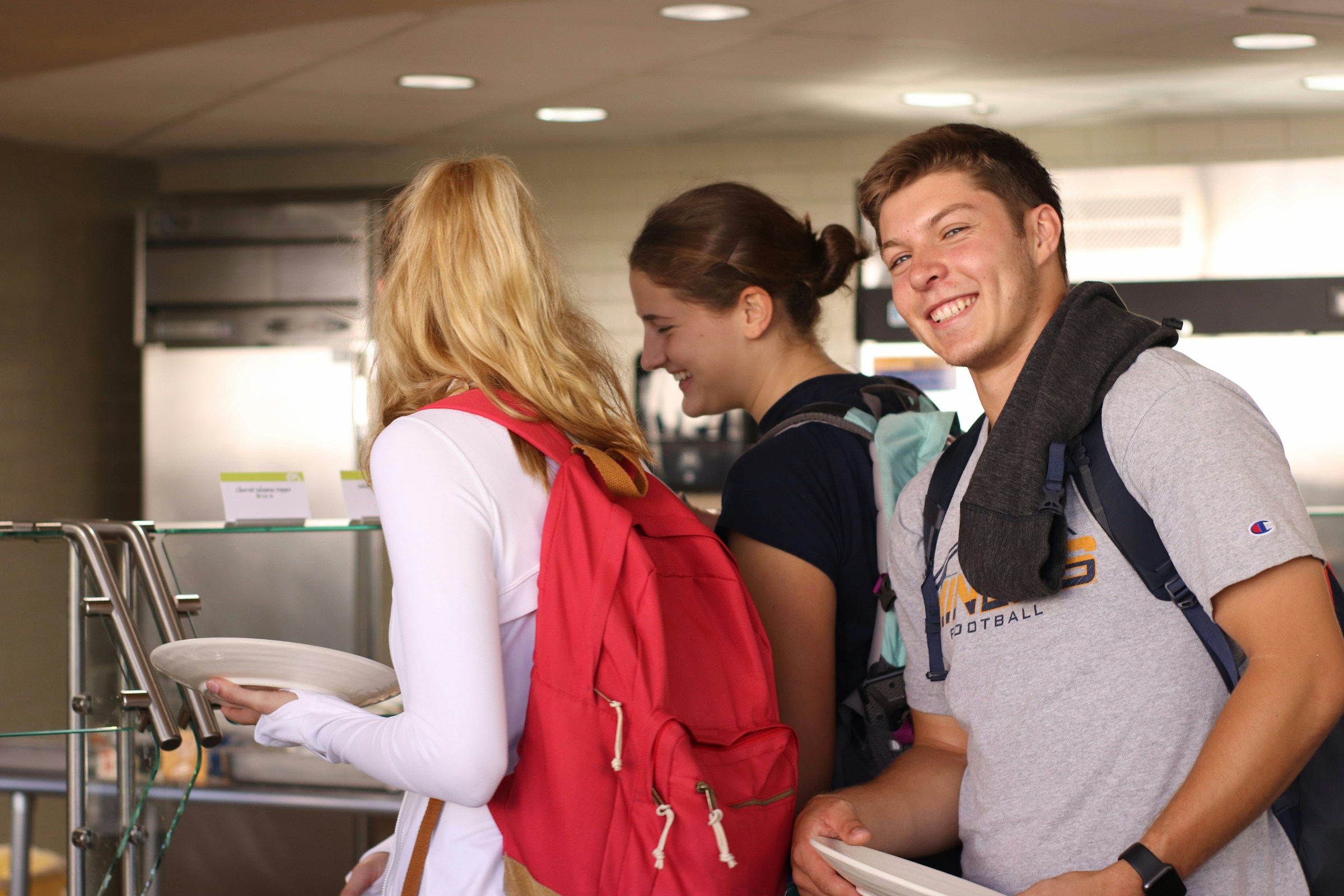 Universitarios sujetando platos en una cafetería | Fuente: Unsplash