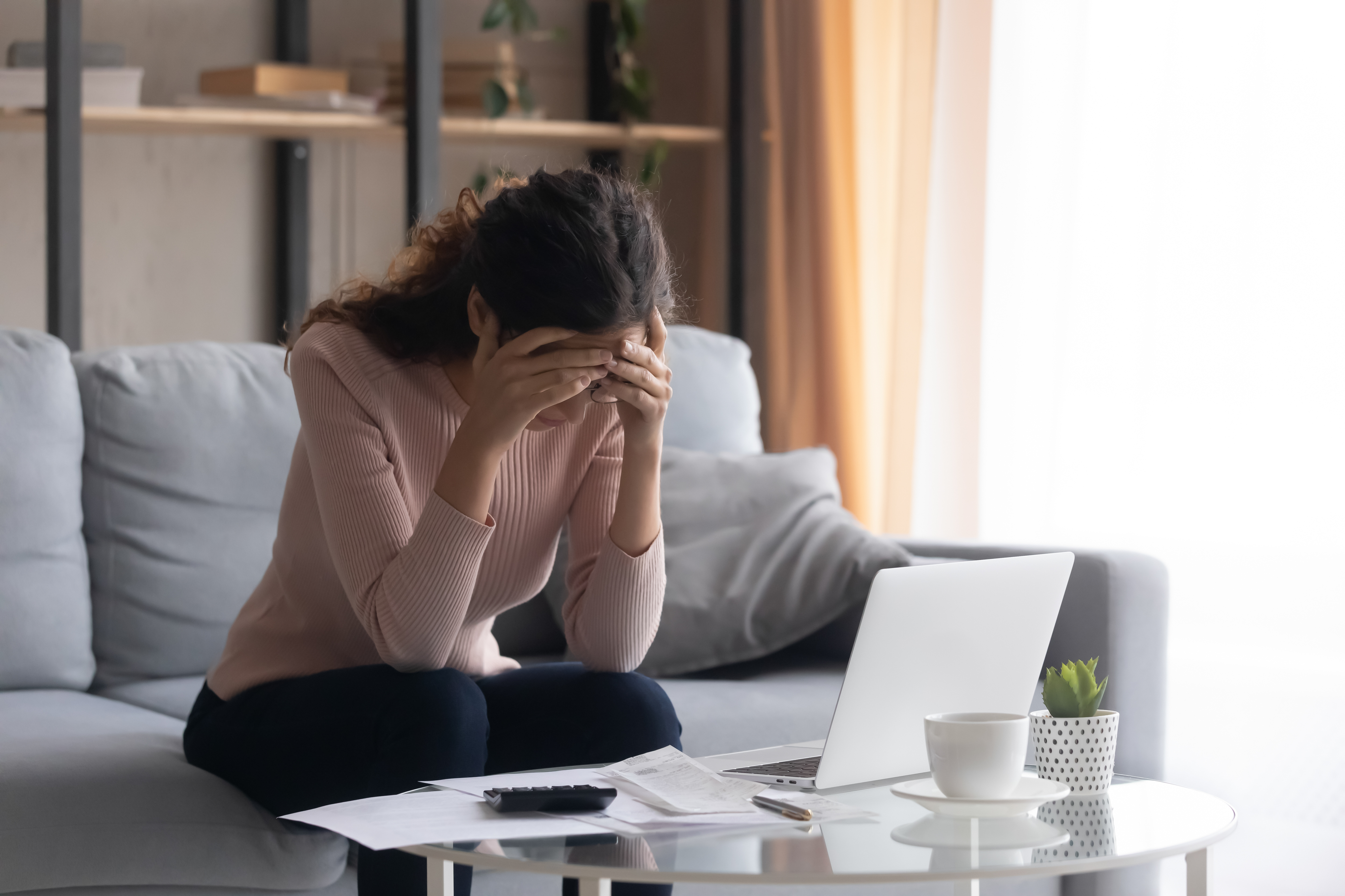 Una mujer parece estresada con una calculadora y un portátil delante | Fuente: Shutterstock