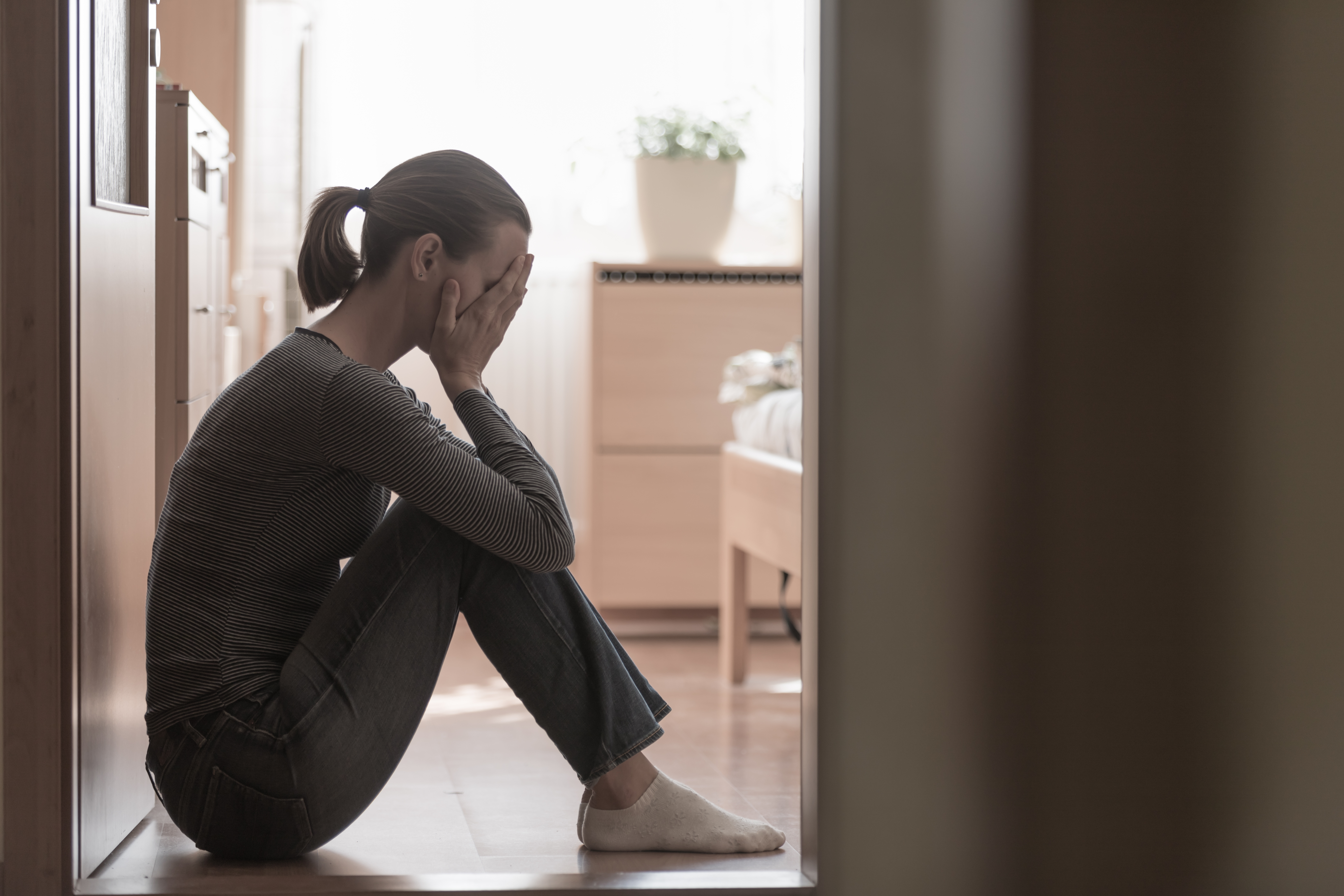 Una mujer sentada en el suelo con las manos tapándose la cara | Foto: Shutterstock