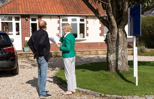 Posibles compradores de casas en la foto viendo una casa con un cartel de venta. | Foto: Getty Images