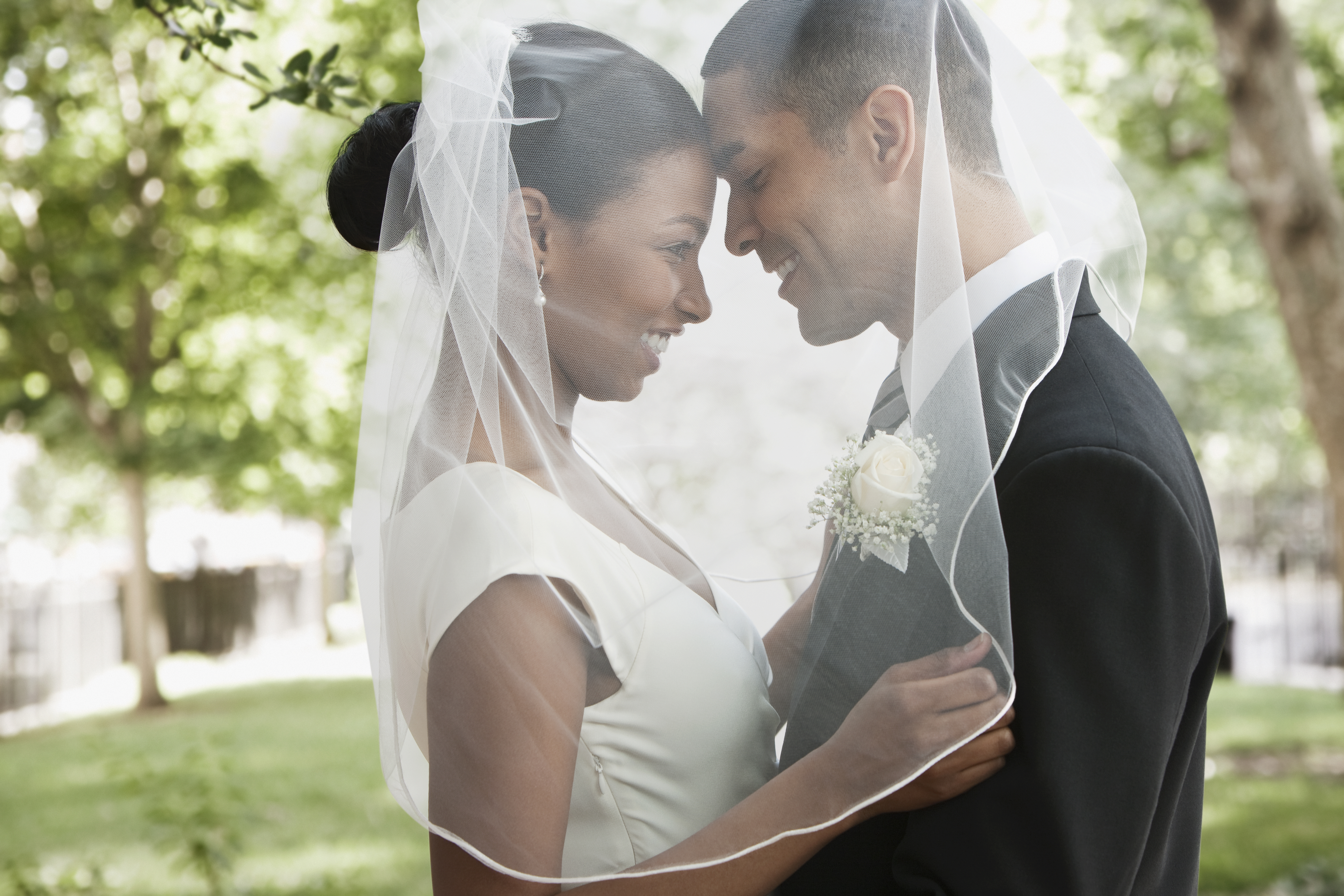 Novia y novio abrazados bajo el velo | Fuente: Getty Images