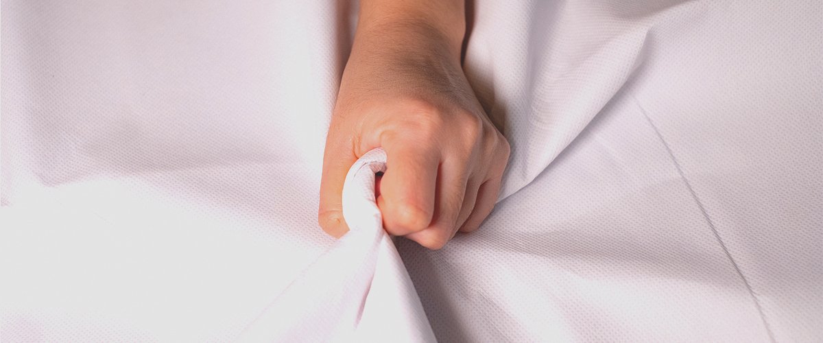 Mano de mujer apretando la sábana. | Foto: Shutterstock