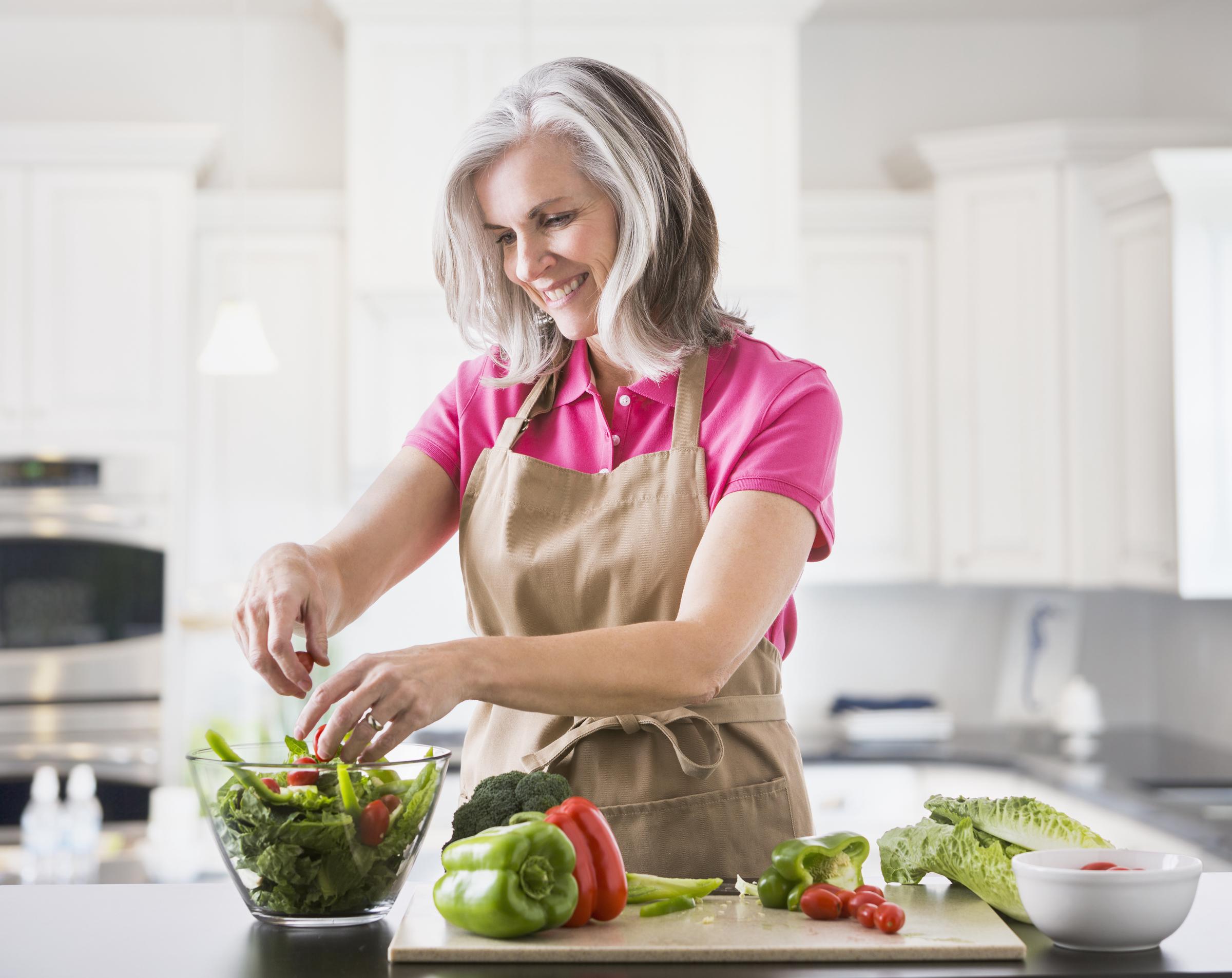 Una mujer mayor preparando una ensalada | Fuente: Getty Images