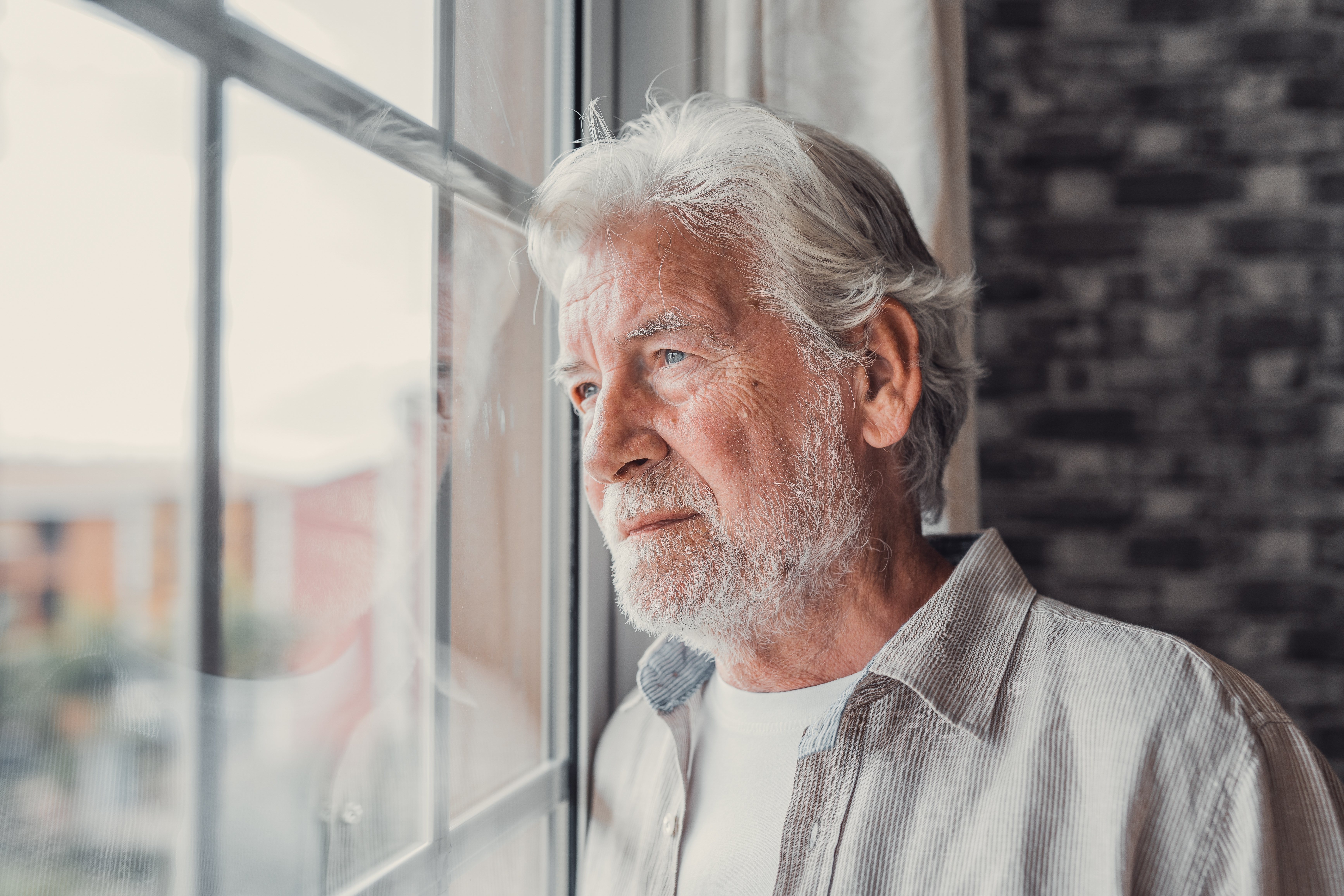 Un anciano preocupado junto a una ventana | Fuente: Shutterstock