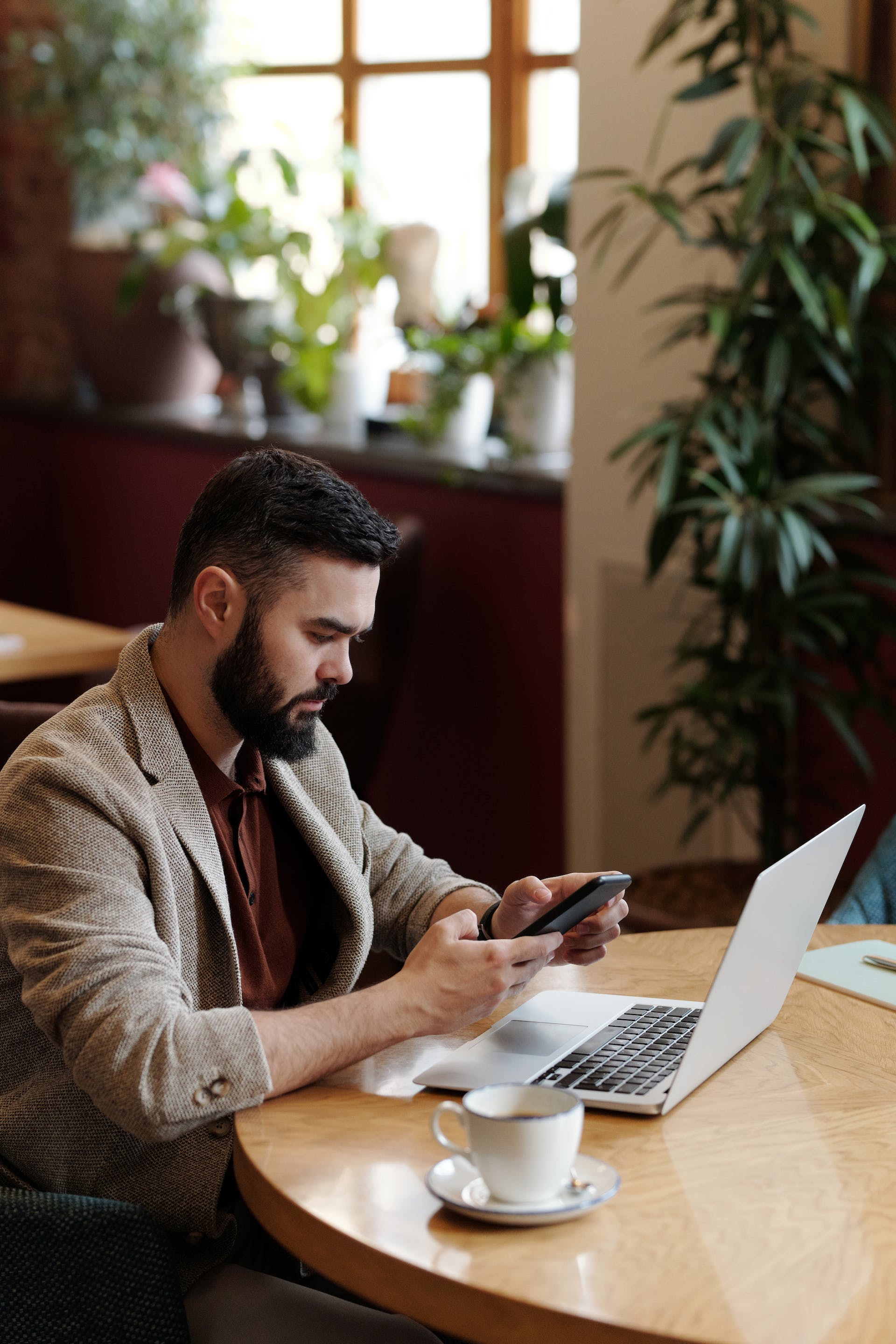 Hombre sentado a la mesa utilizando su teléfono. | Fuente: Pexels