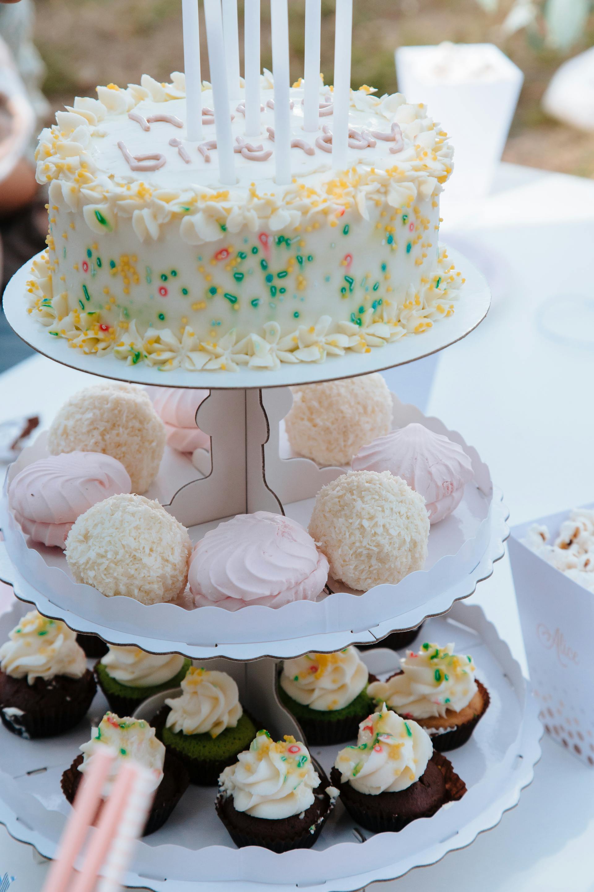 Pastelitos y tarta de cumpleaños en un soporte para tartas | Fuente: Pexels