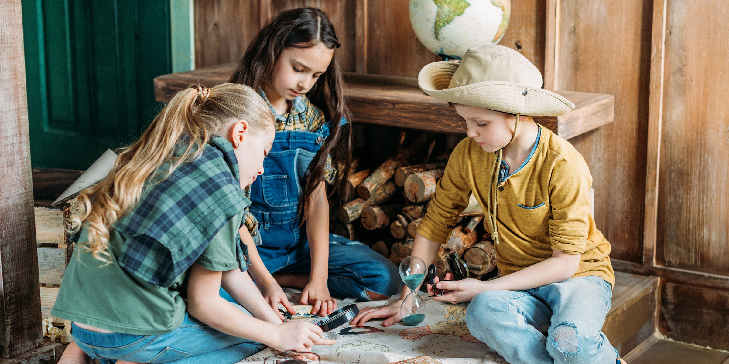 Tres niños jugando con un mapa | Fuente: Shutterstock