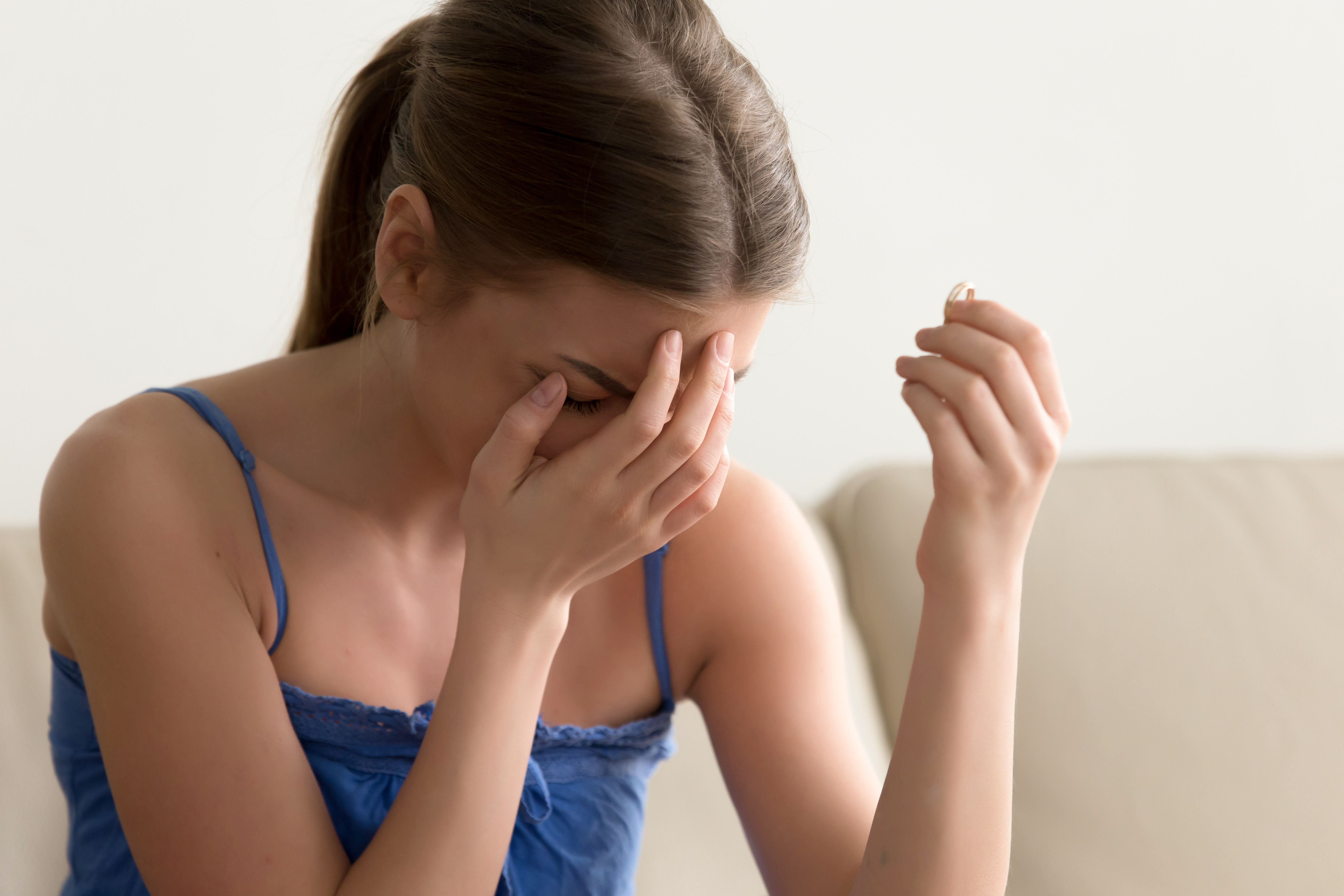 Mujer llorando mientras sostiene su anillo de compromiso | Foto: Shutterstock
