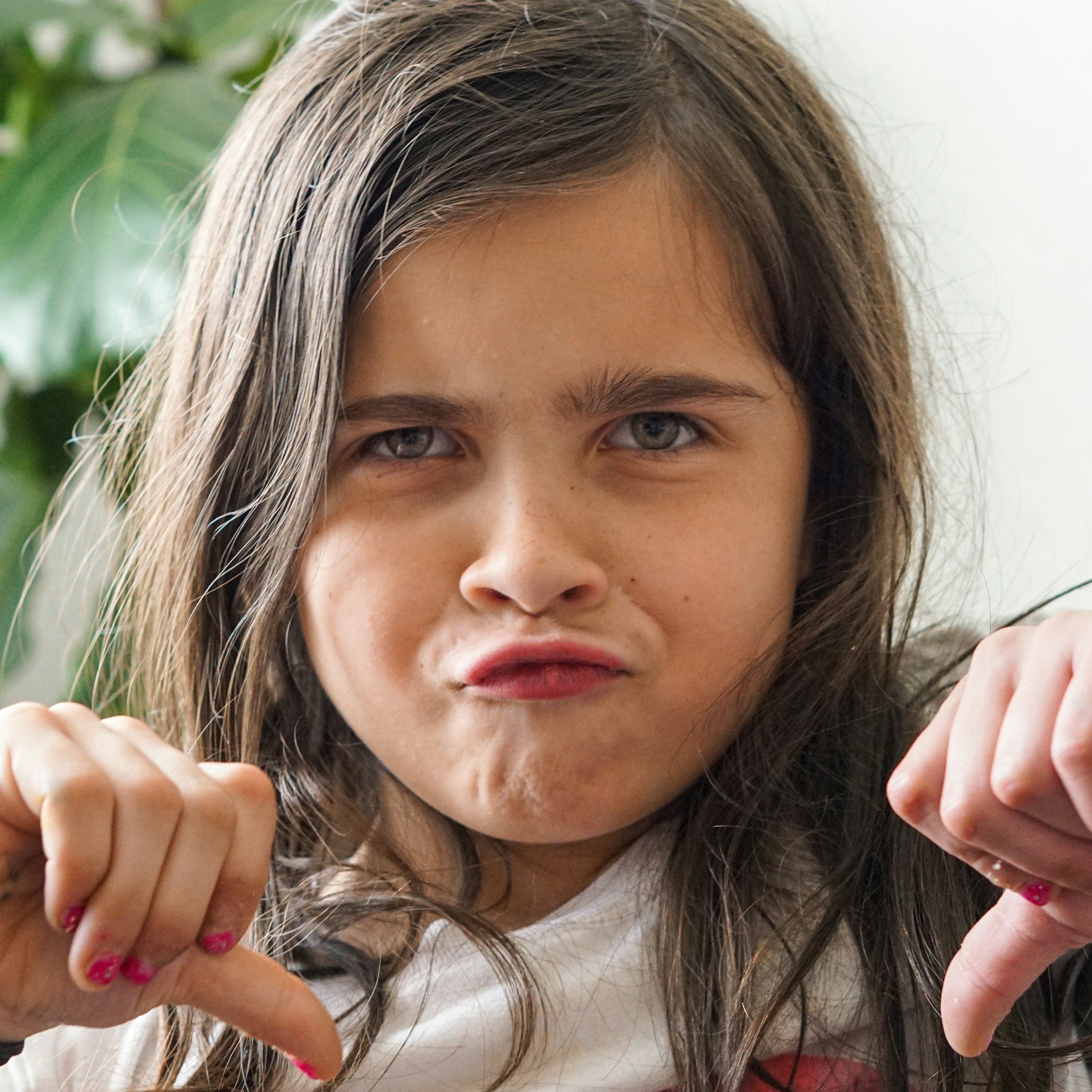 Una niña enfadada mostrando los pulgares hacia abajo | Fuente: Unsplash