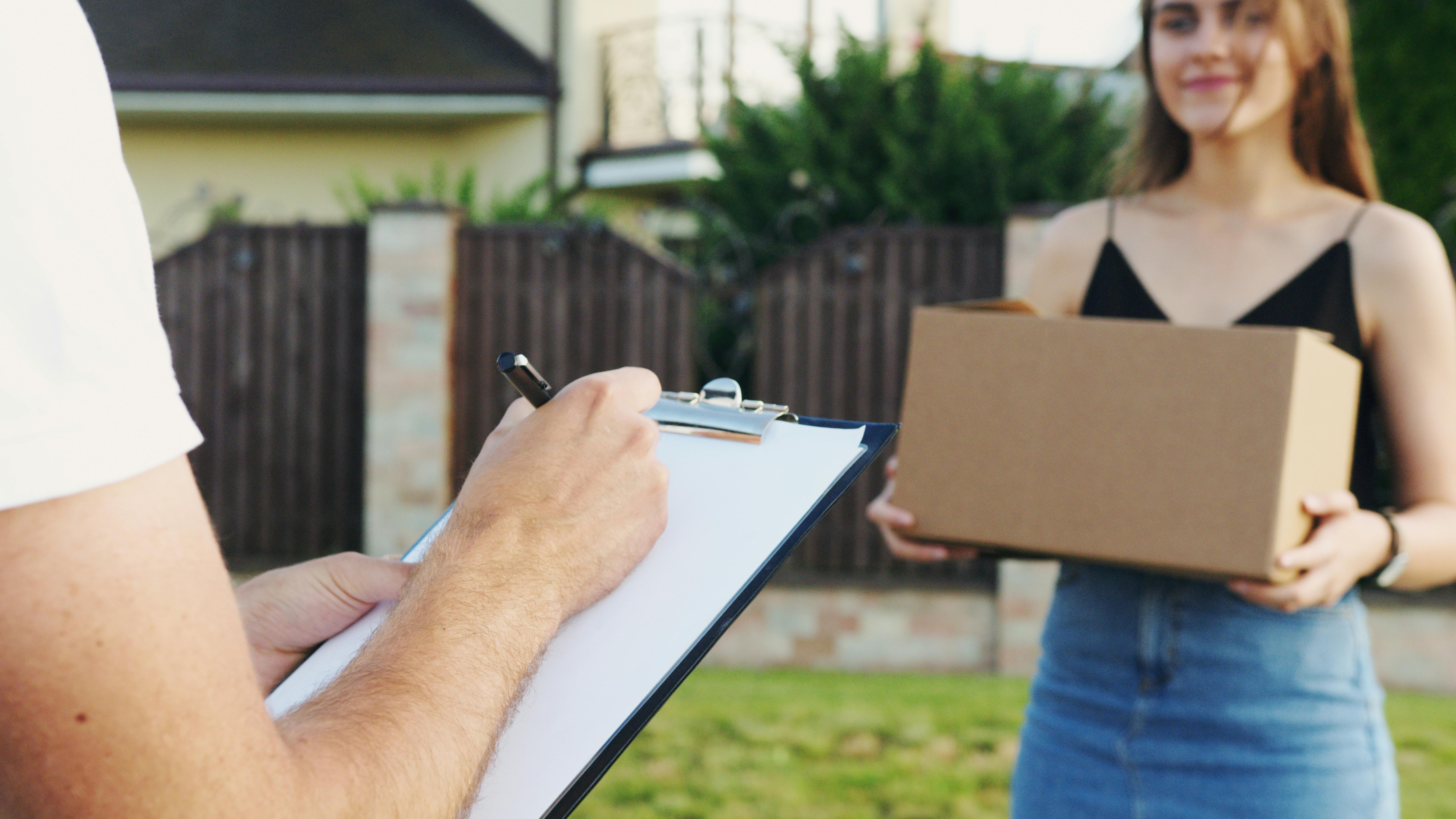 Una mujer sostiene una caja con un hombre escribiendo algo | Fuente: Pexels