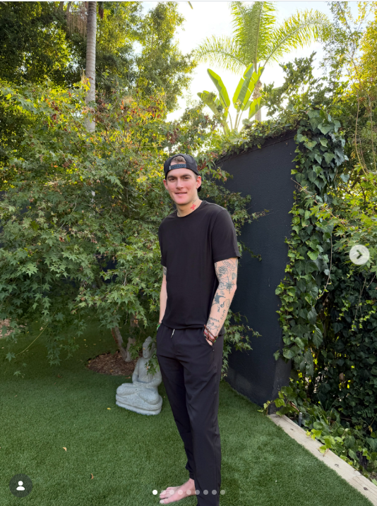 Presley Gerber posa descalzo en un frondoso jardín el 6 de agosto de 2026, con un conjunto totalmente negro y una gorra de béisbol puesta al revés, mientras comparte un momento relajado de su vida lejos de los actos públicos. | Fuente: Instagram/presleygerber