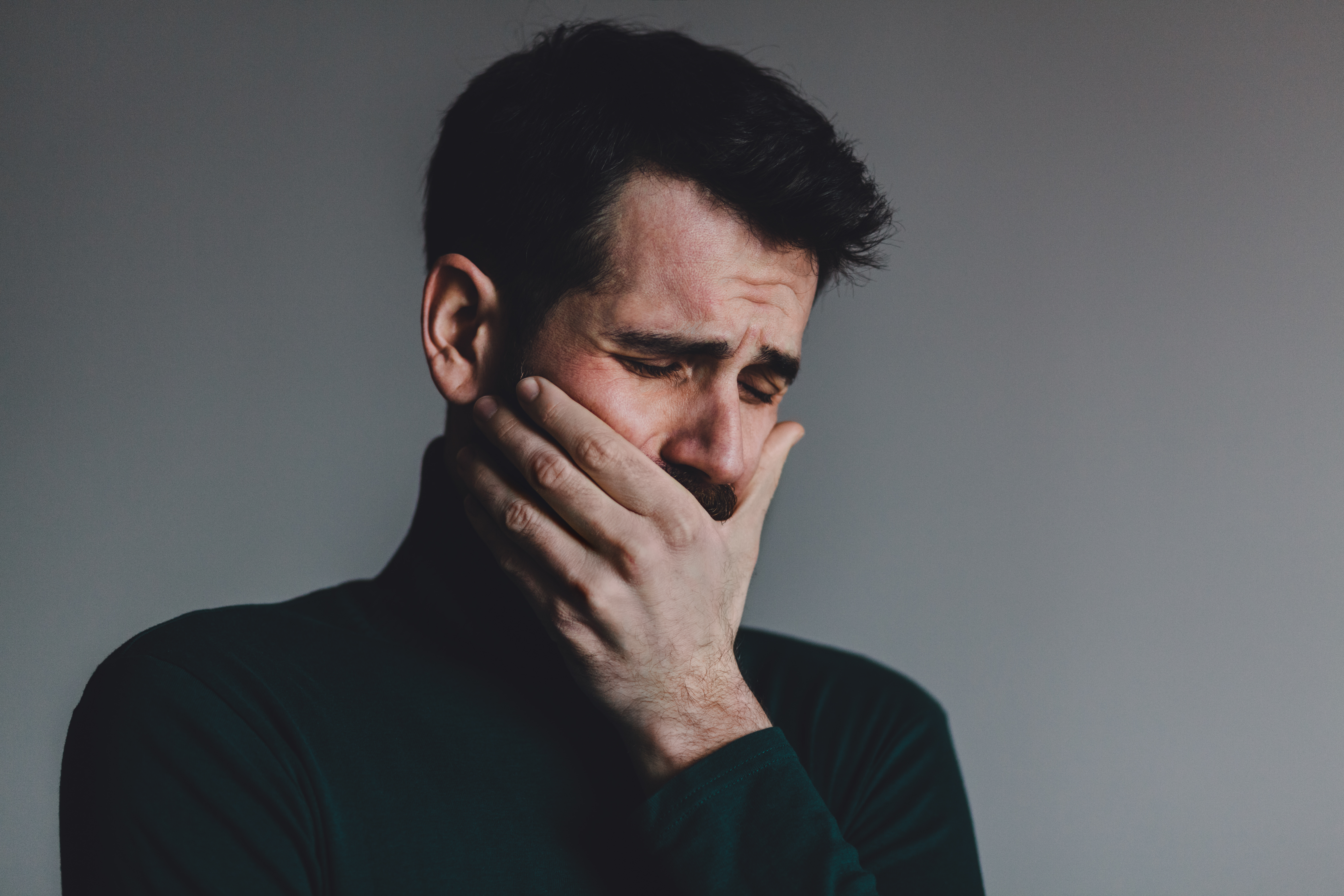 Un hombre se sujeta la boca mientras llora | Foto: Shutterstock
