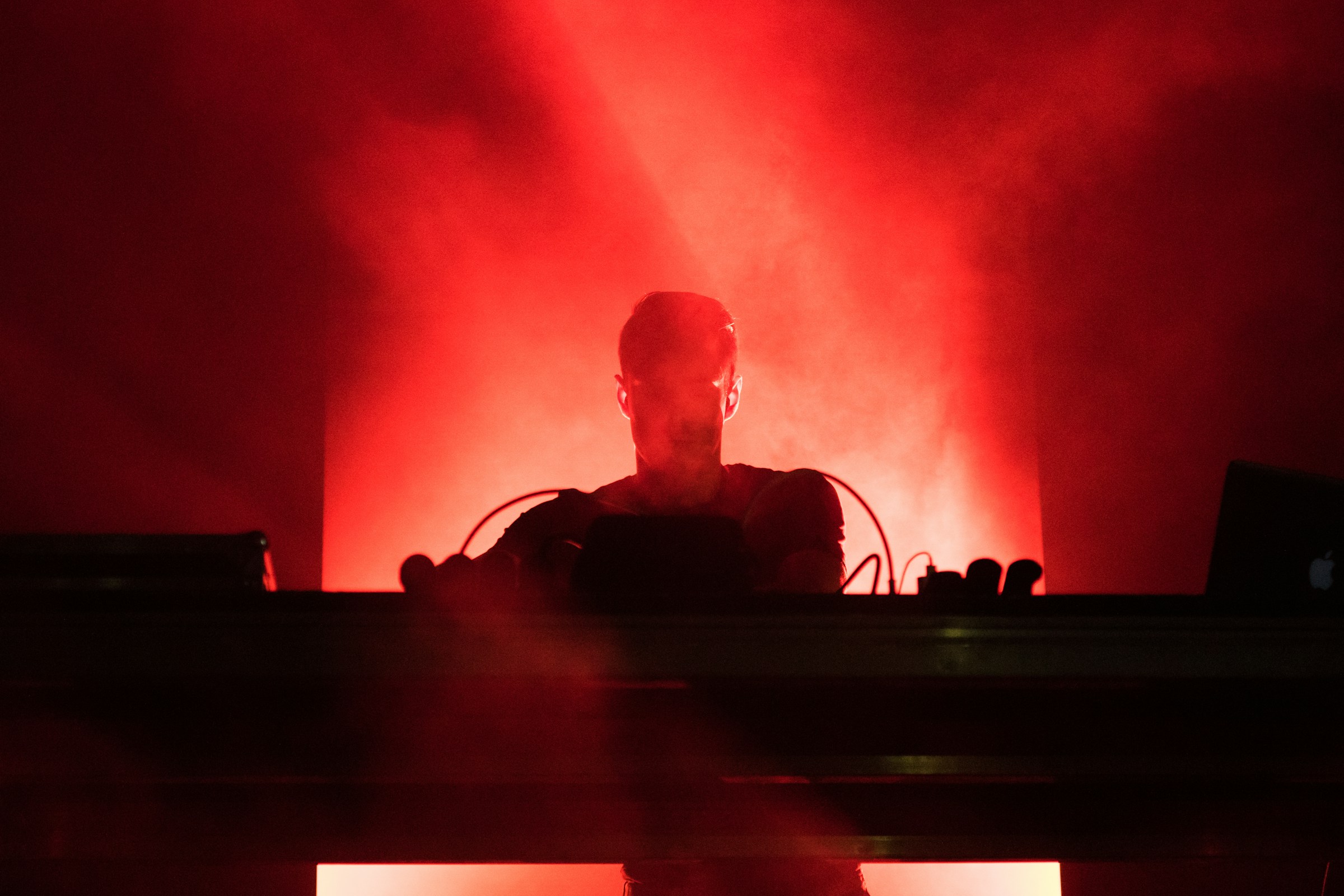 DJ tocando música con luces rojas | Foto: Unsplash