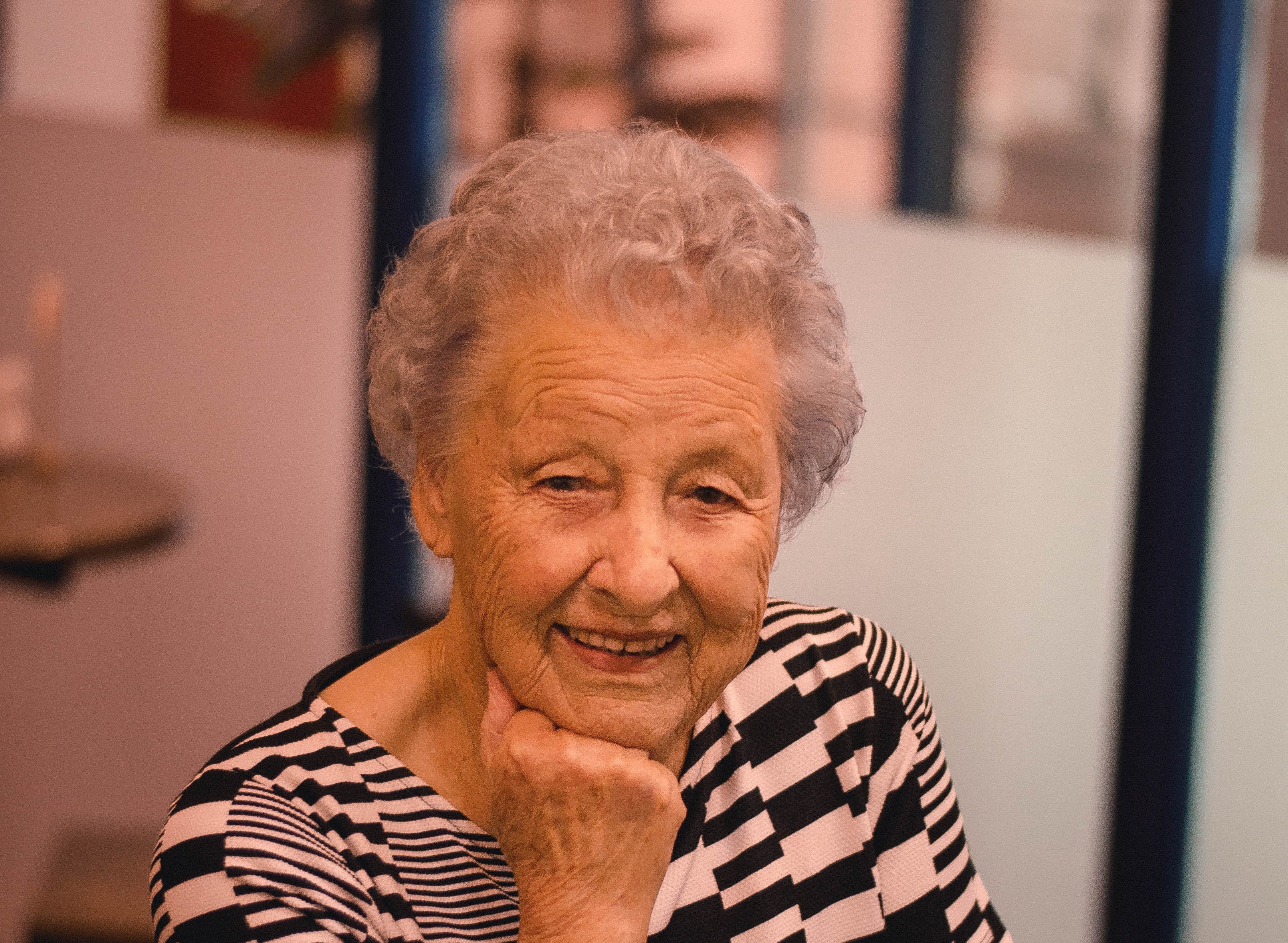 Una anciana sonriendo con la mano en su quijada. | Foto: Pexels
