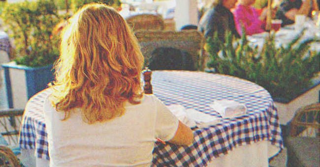Una mujer sentada en la mesa de un restaurante al aire libre | Fuente: Shutterstock