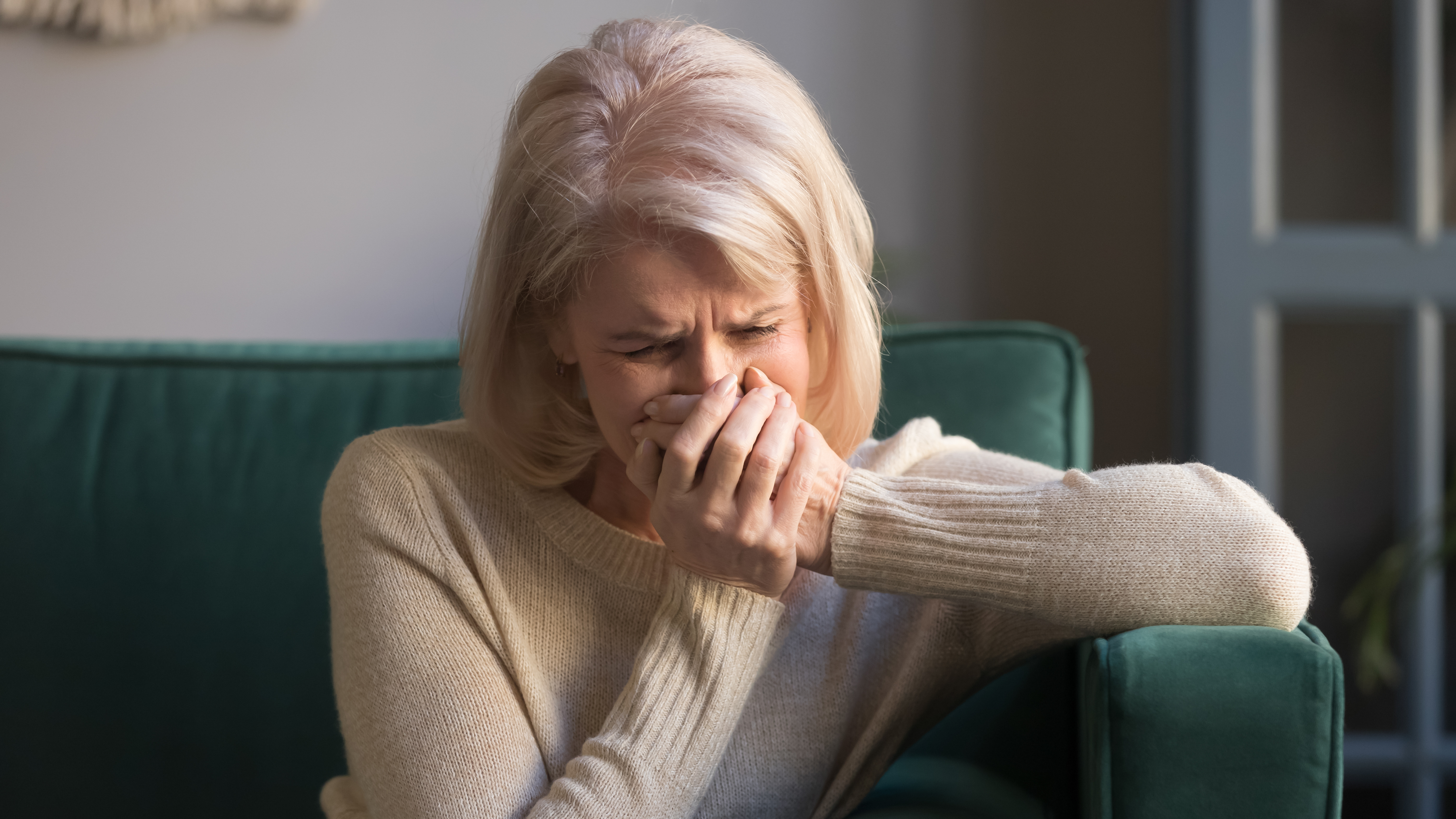 Mujer mayor llora sentada en el sofá | Foto: Shutterstock