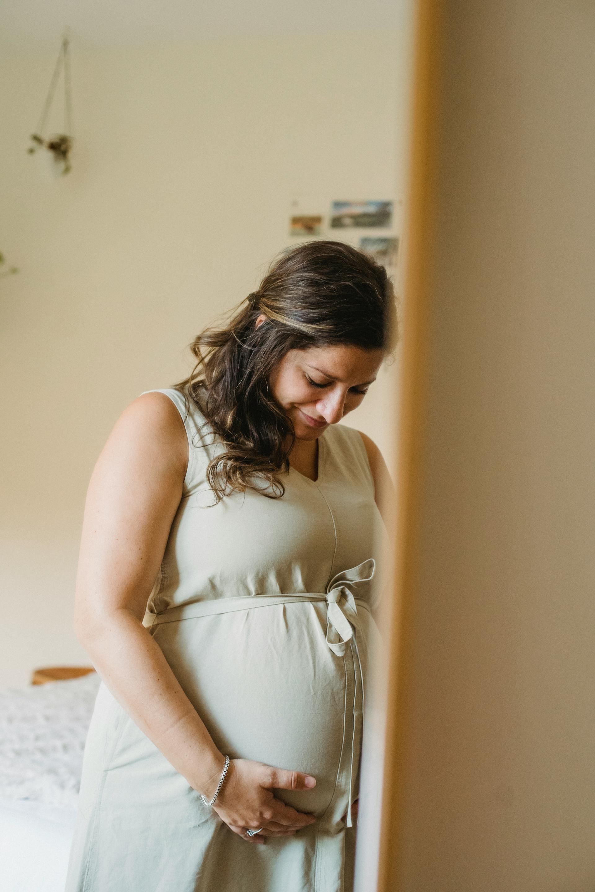 Una mujer sonriendo a su barriga de embarazada | Fuente: Pexels