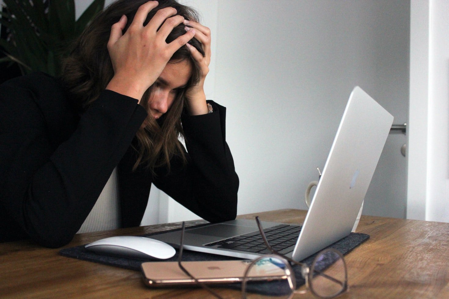Mujer agobiada con las manos en su cabeza trabajando en una computadora portátil. | Foto: Unsplash