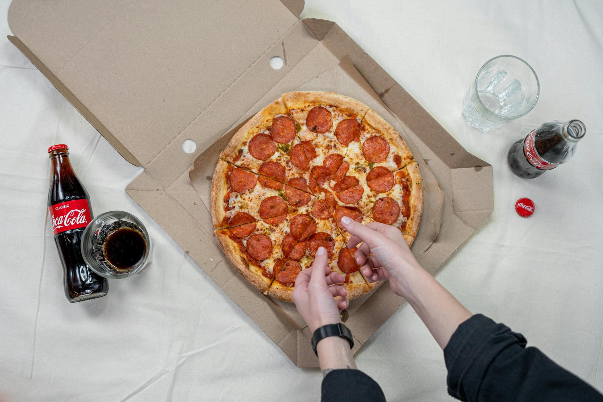 Una persona tomando un trozo de pizza | Fuente: Pexels