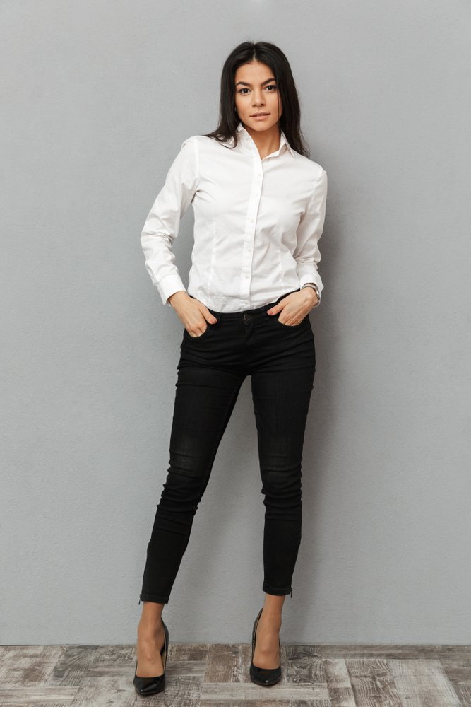 Mujer usando pantalones negros ceñidos al cuerpo y una camisa blanca. | Foto: Shutterstock