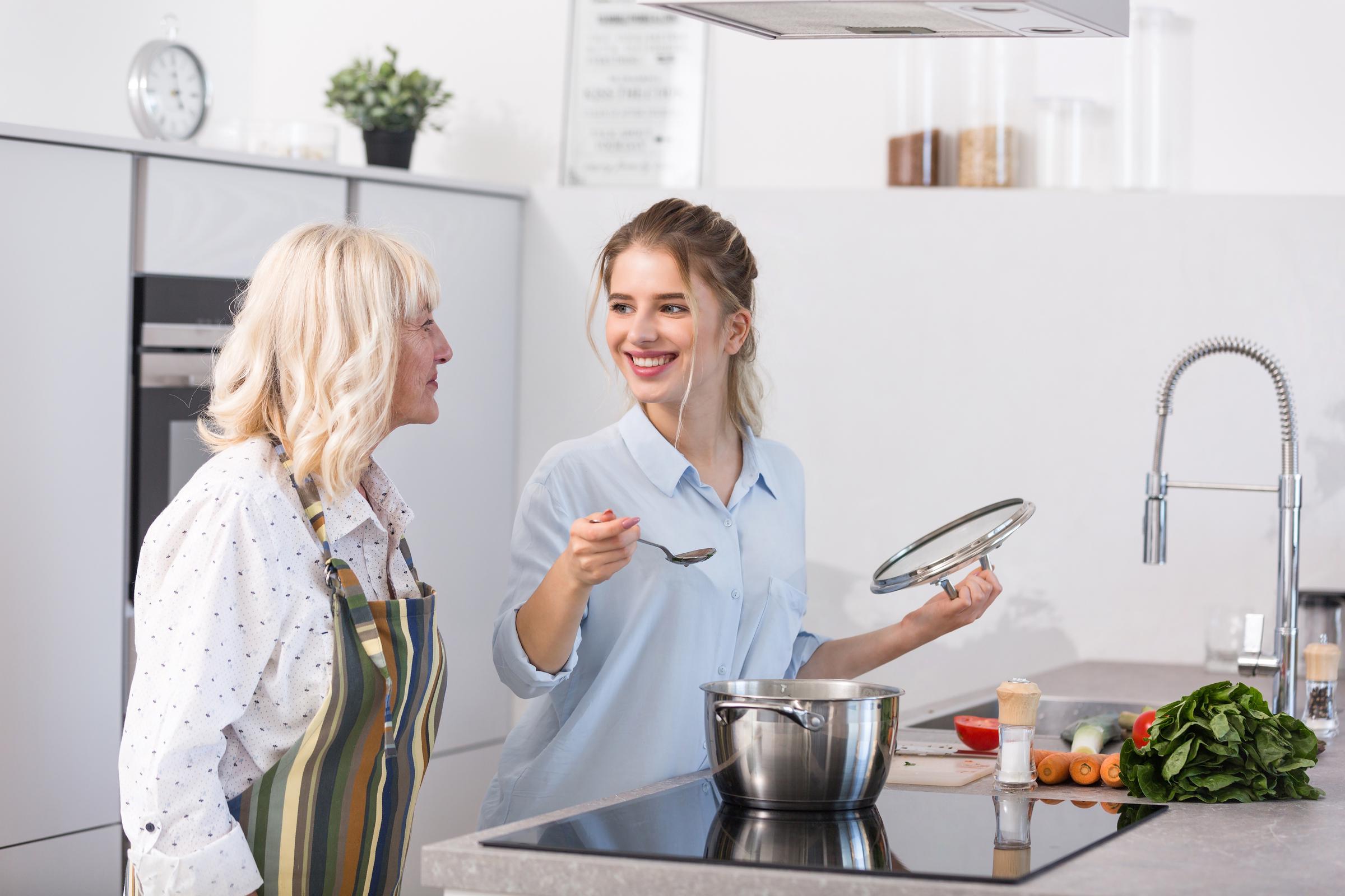 Una mujer sonriente hablando con una mujer mayor en la cocina | Fuente: Freepik