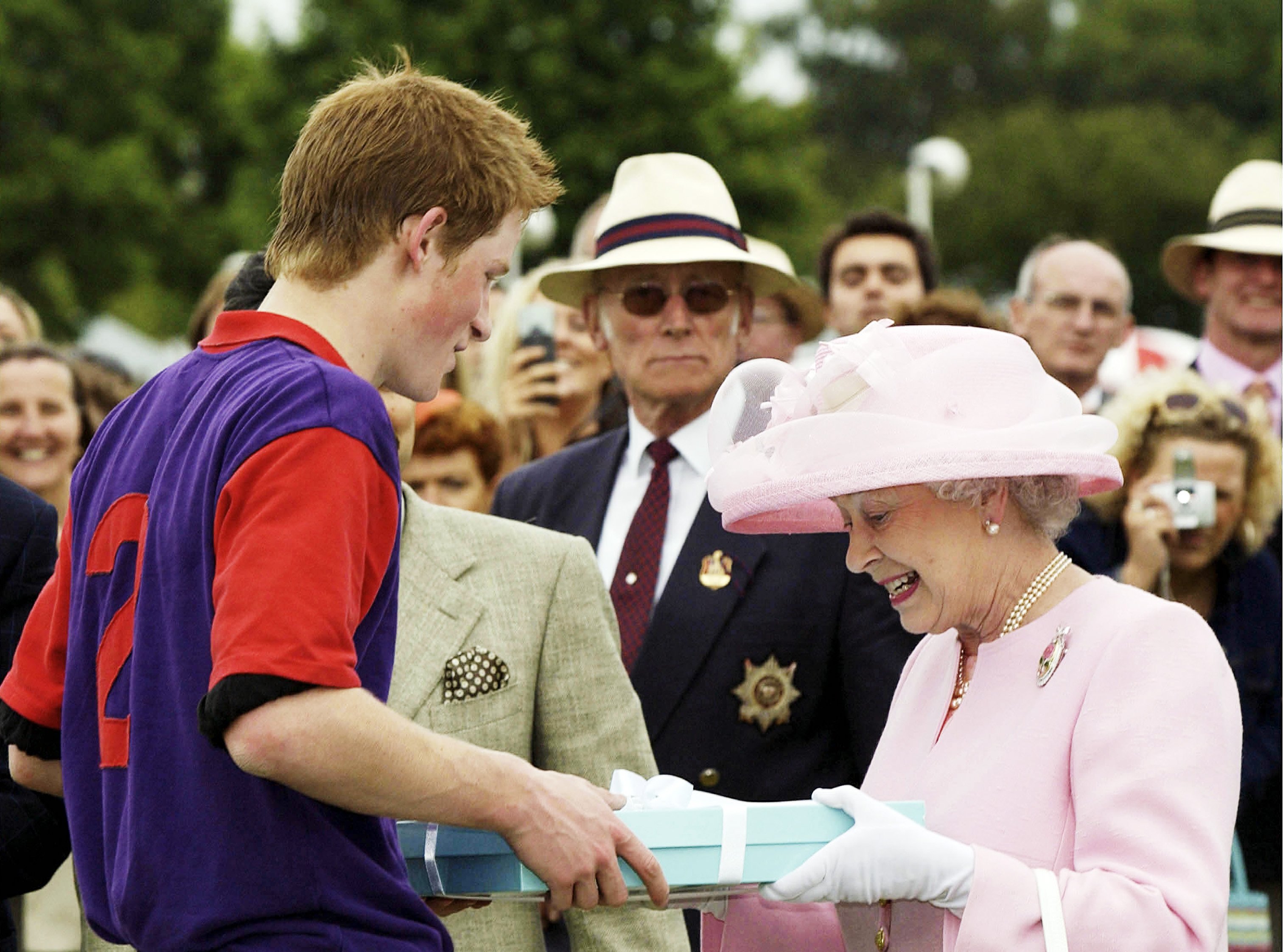 La reina Elizabeth II haciendo una presentación al príncipe Harry después de un partido de polo durante el Royal Ascot, el 18 de junio de 2003 en Windsor, Inglaterra. | Foto: Getty Images