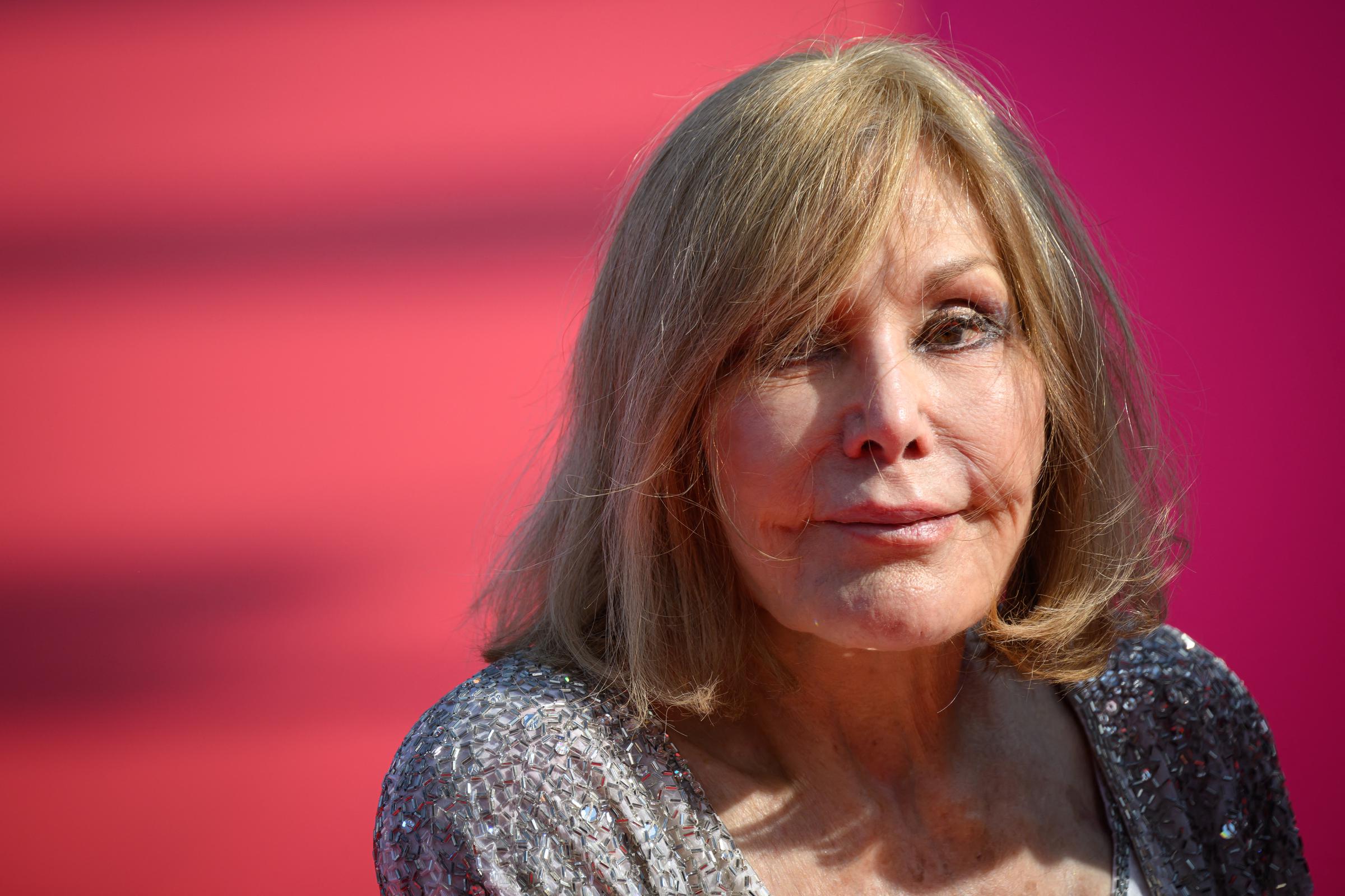 Kim Novak posa para un primer plano en la 51.ª edición del Festival de Cine Americano de Deauville, el 6 de septiembre de 2025, con un vestido plateado brillante y un escote pronunciado. Su melena rubia, que le llega hasta los hombros, le enmarca el rostro sobre un fondo rosa y rojo. | Fuente: Getty Images