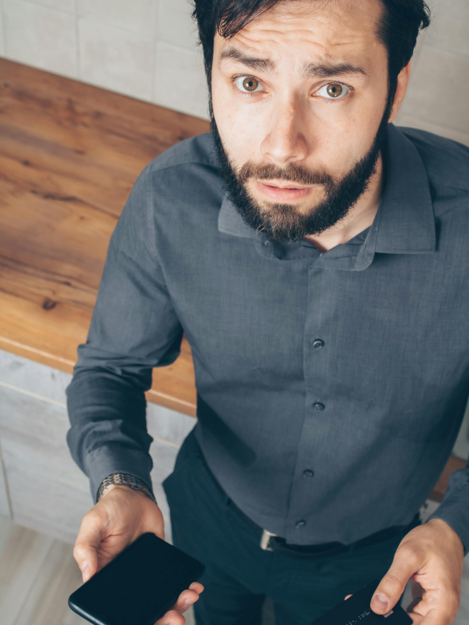 Un uomo dall'aria confusa mentre tiene in mano il suo smartphone | Fonte: Pexels