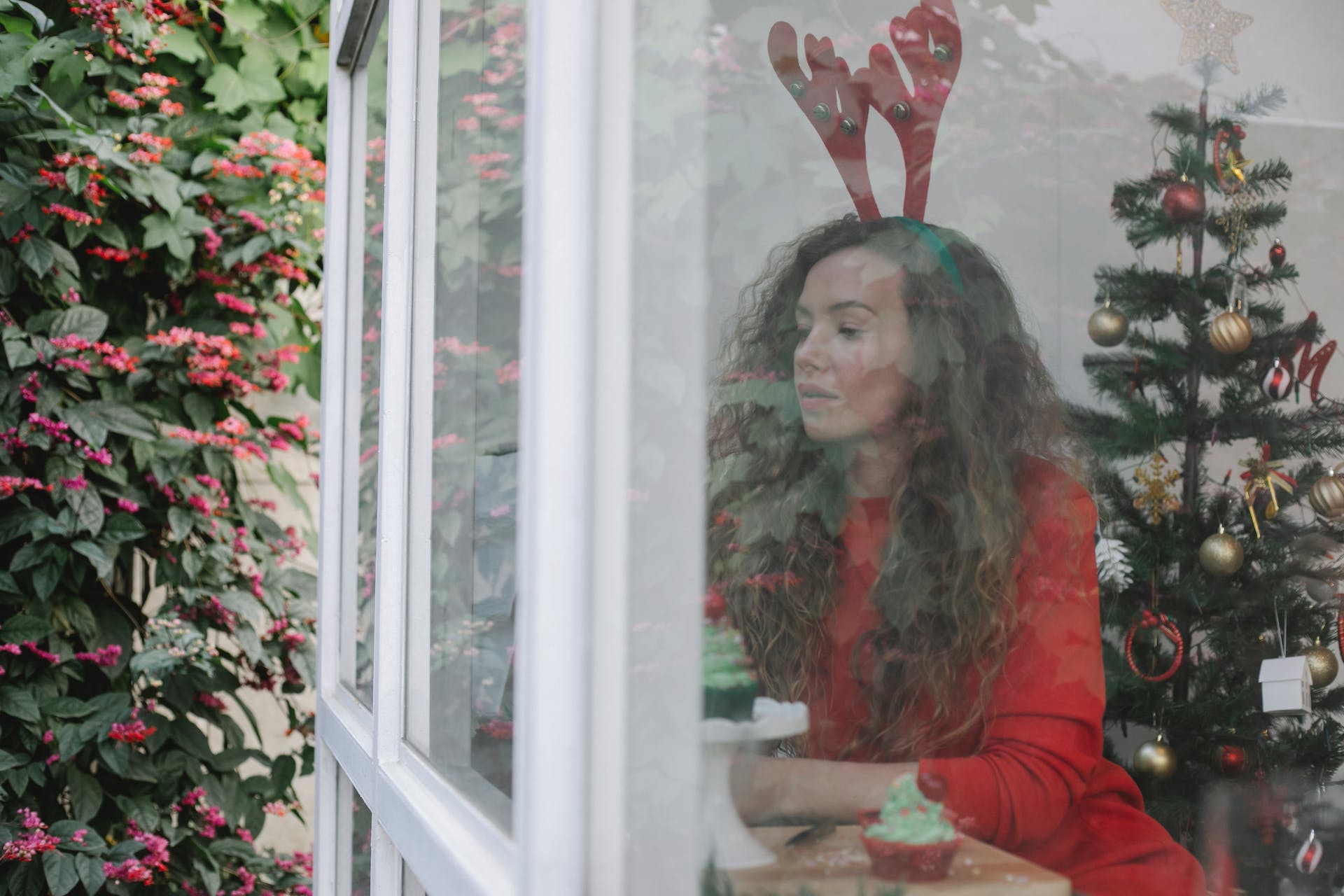 Mujer mirando por la ventana en Navidad | Foto: Pexels
