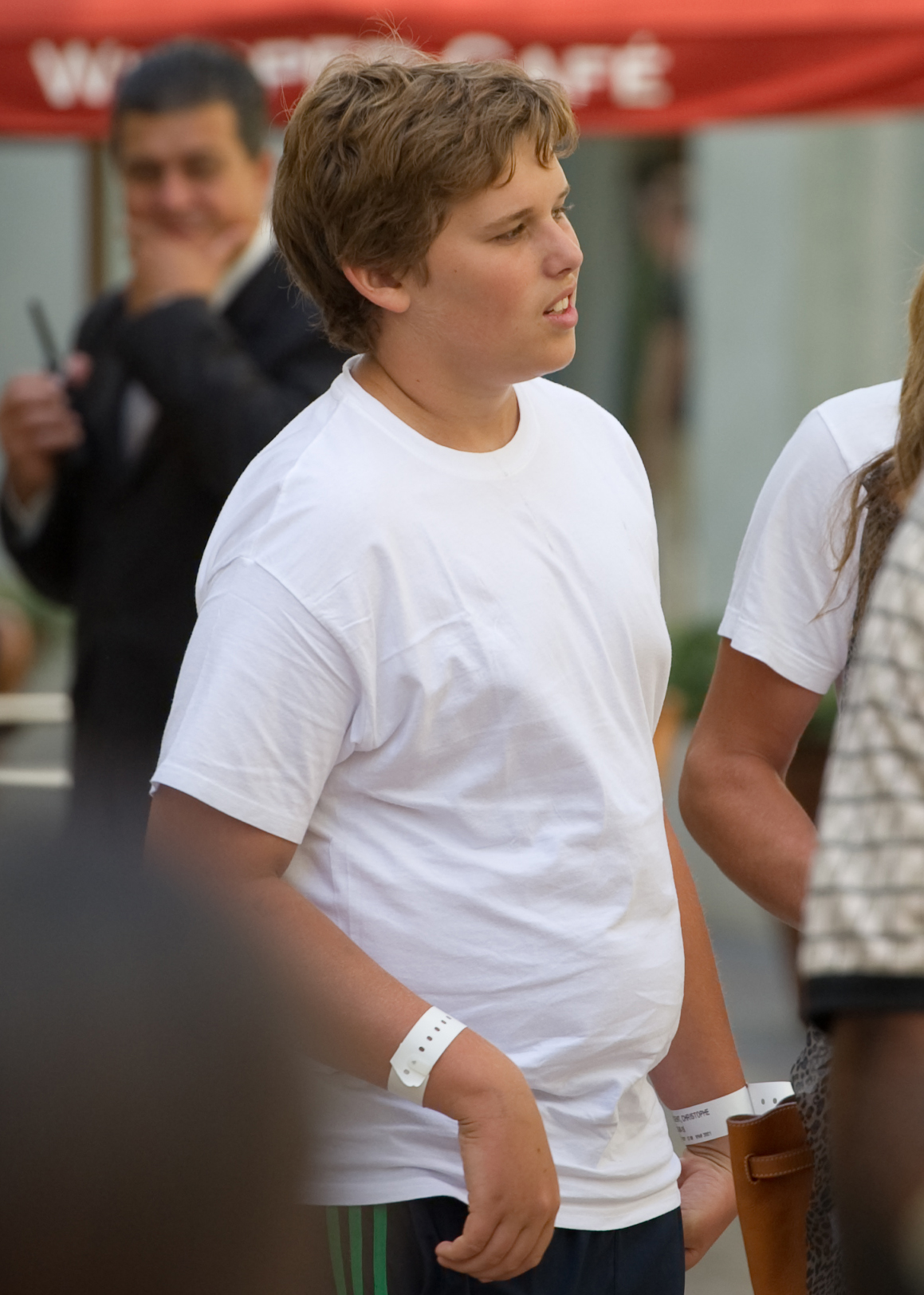 Christopher Schwarzenegger aparece en The Grove, en Los Ángeles, el 27 de julio de 2011. Con una sencilla camiseta blanca y pantalones deportivos oscuros, aparece en plena adolescencia, de pie entre otras personas en un ambiente relajado.
