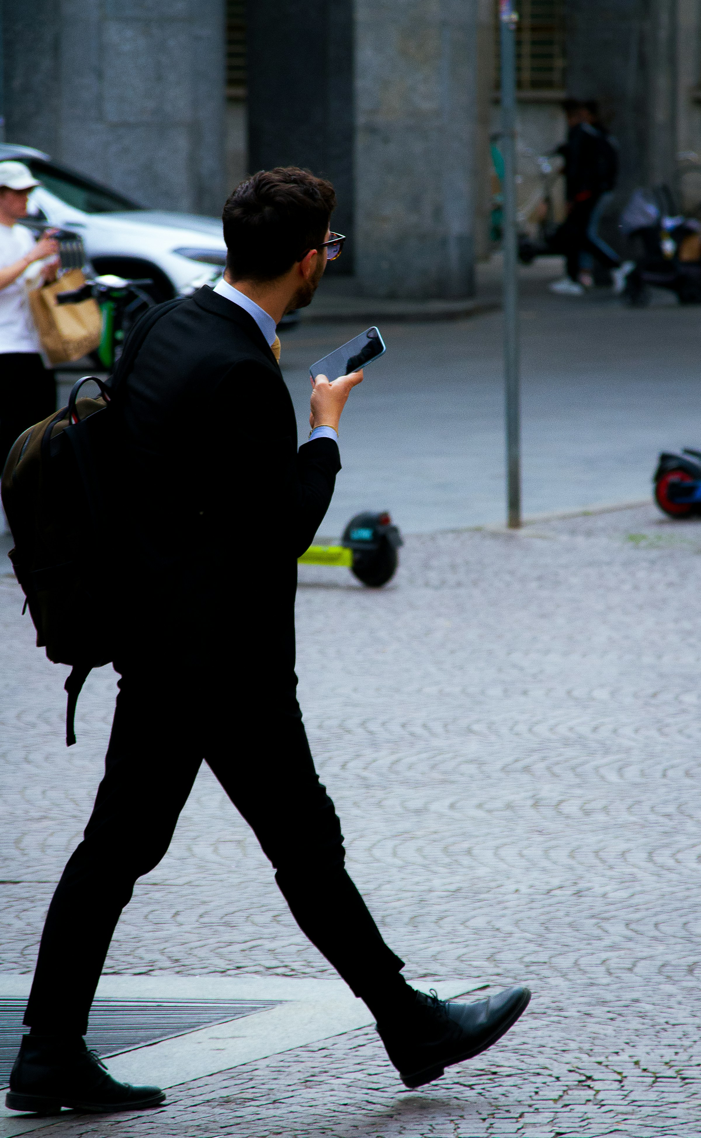 Hombre de negocios caminando por la calle con el teléfono en la mano | Foto: Unsplash