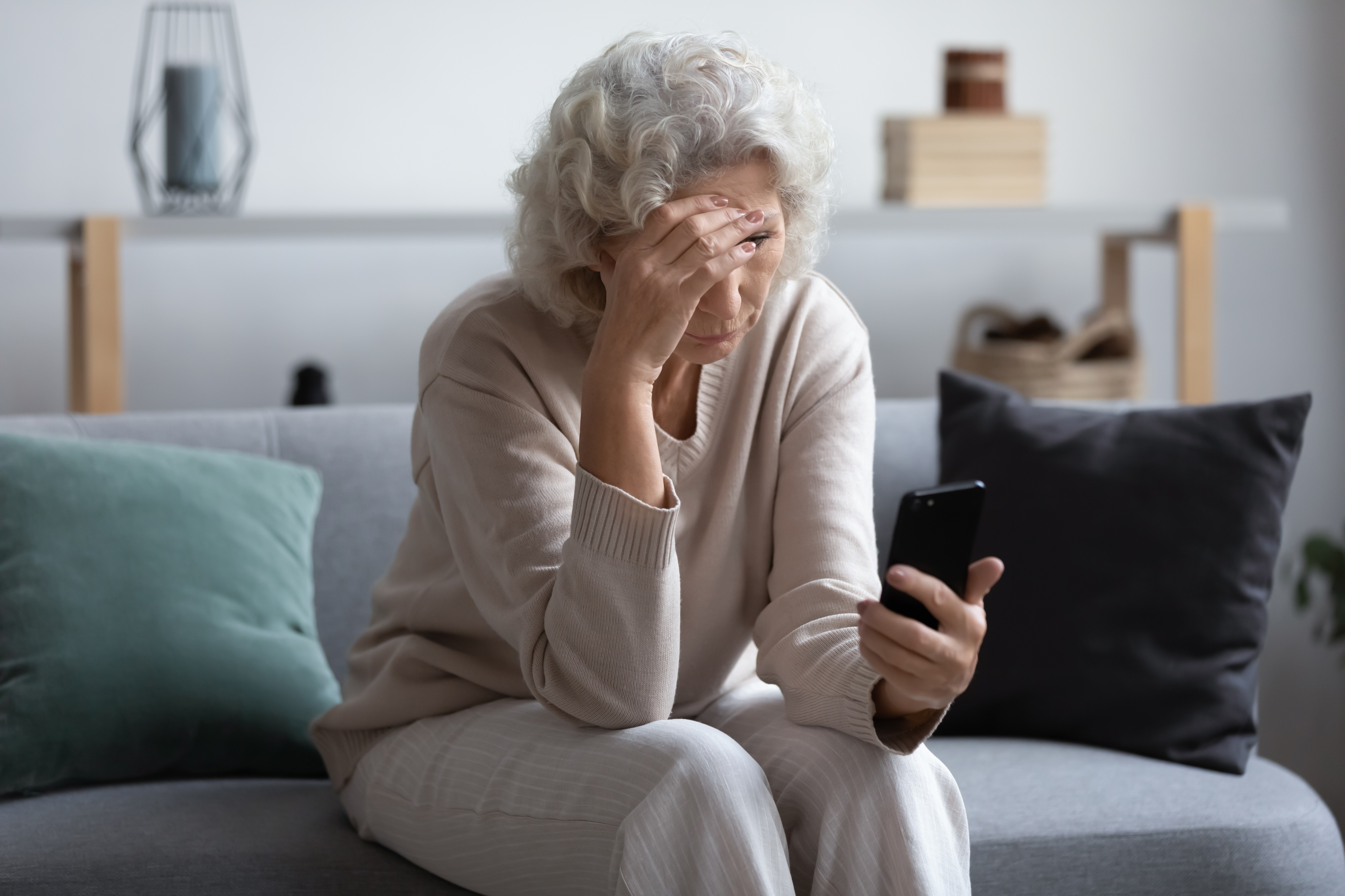 Una mujer mayor infeliz mirando la pantalla de su teléfono | Foto: Shutterstock
